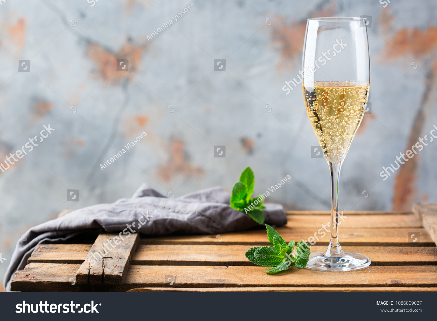Food and drink, holidays party concept. Cold fresh alcohol beverage champagne sparkling white wine with bubbles in a flute glass on a wooden table. Copy space background #1086809027
