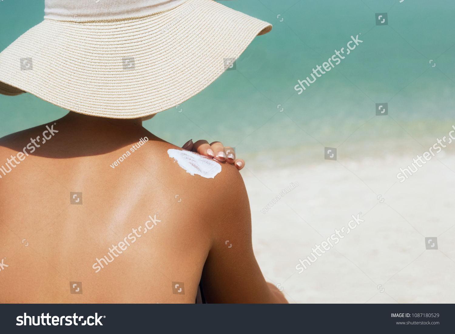 Woman applying sunscreen creme on  tanned  shoulder. Skincare. Body Sun protection suncream. Bikini hat woman applying moisturizing sunscreen lotion on back. #1087180529