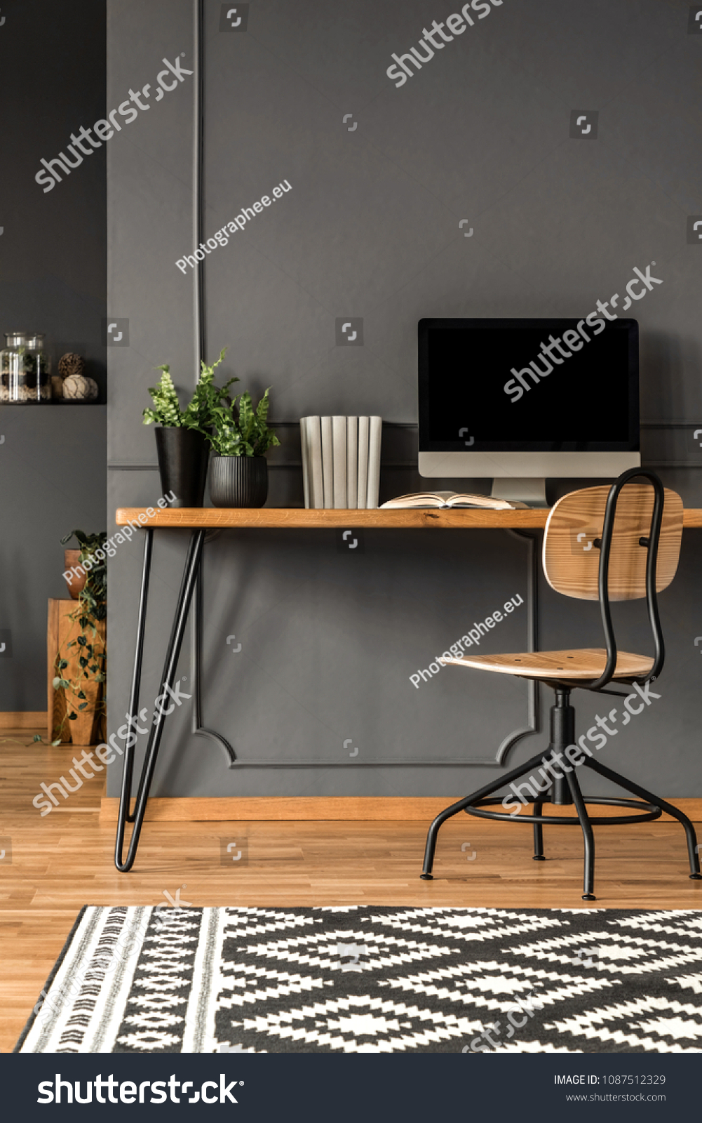 Patterned carpet in grey scandi workspace interior with computer monitor on wooden desk #1087512329