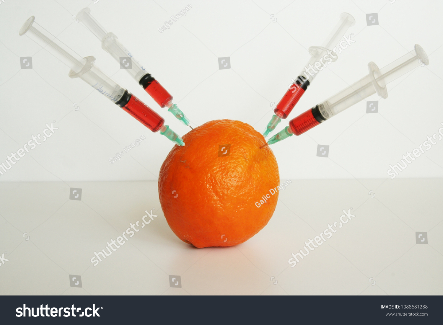 Orange fruit with syringes on it. GMO fruit. GMO food ingredient. #1088681288