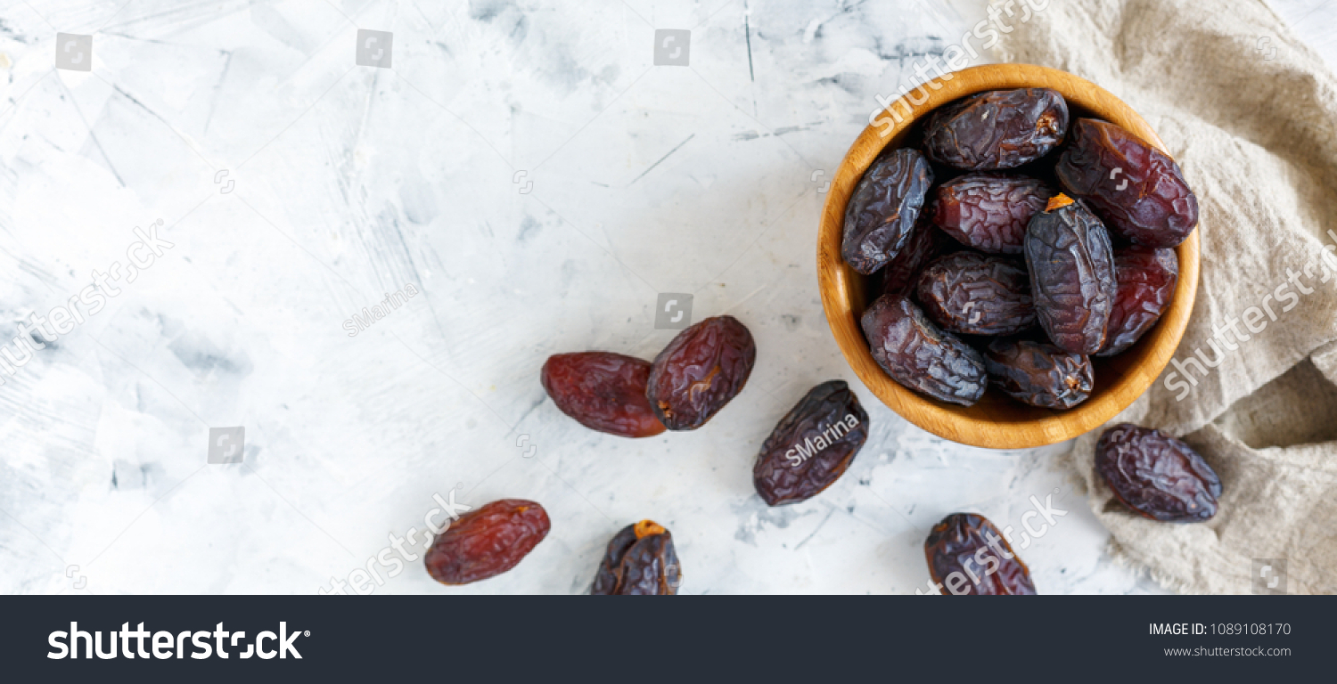 Bowl of dates and a linen cloth on a white concrete background. The view from the top. #1089108170