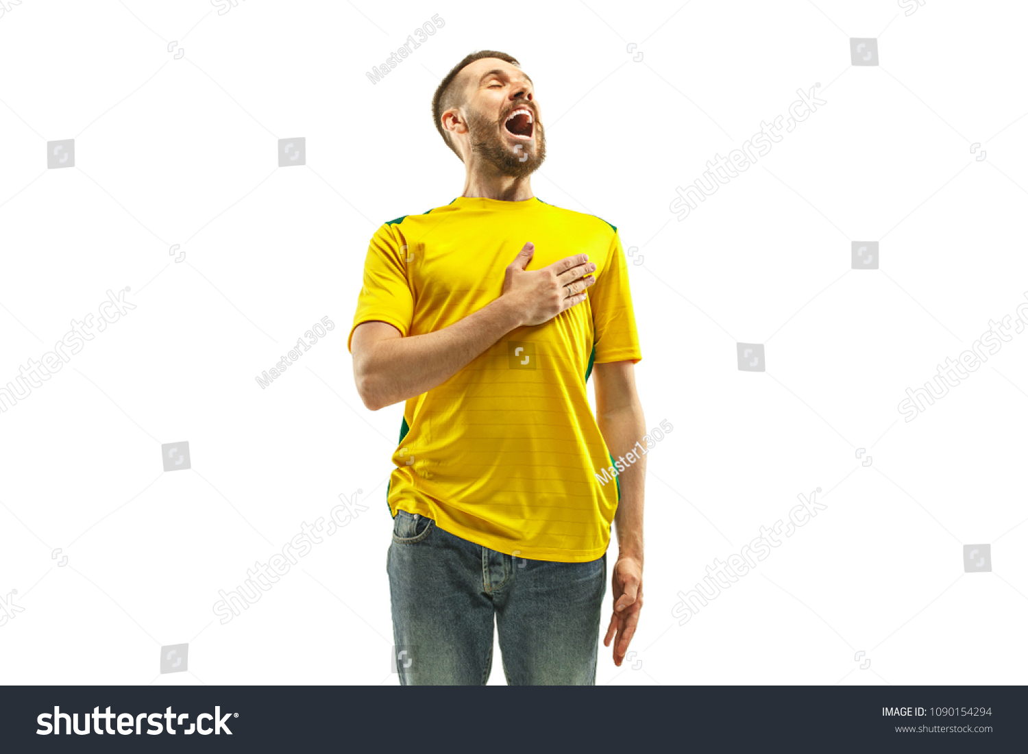 Brazilian fan celebrating on white background. The young man in soccer football uniform standing and singing a hymn at white studio. Fan, support concept. Human emotions concept. #1090154294