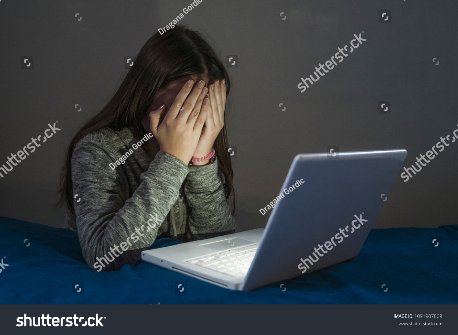 Teenager girl suffering internet cyber bullying scared and depressed cyberbullying. Image of despair girl humilated on internet by classmate. Young teenage girl crying in front of the laptop #1091907869