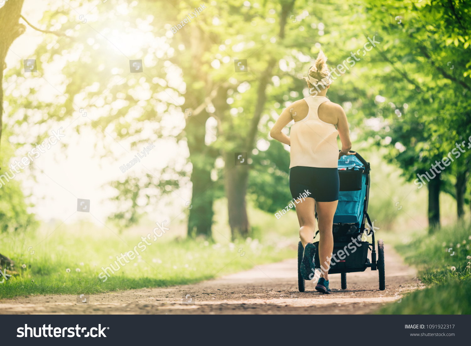 Running woman with baby stroller enjoying summer day in park. Jogging or power walking supermom, active family with baby jogger. #1091922317
