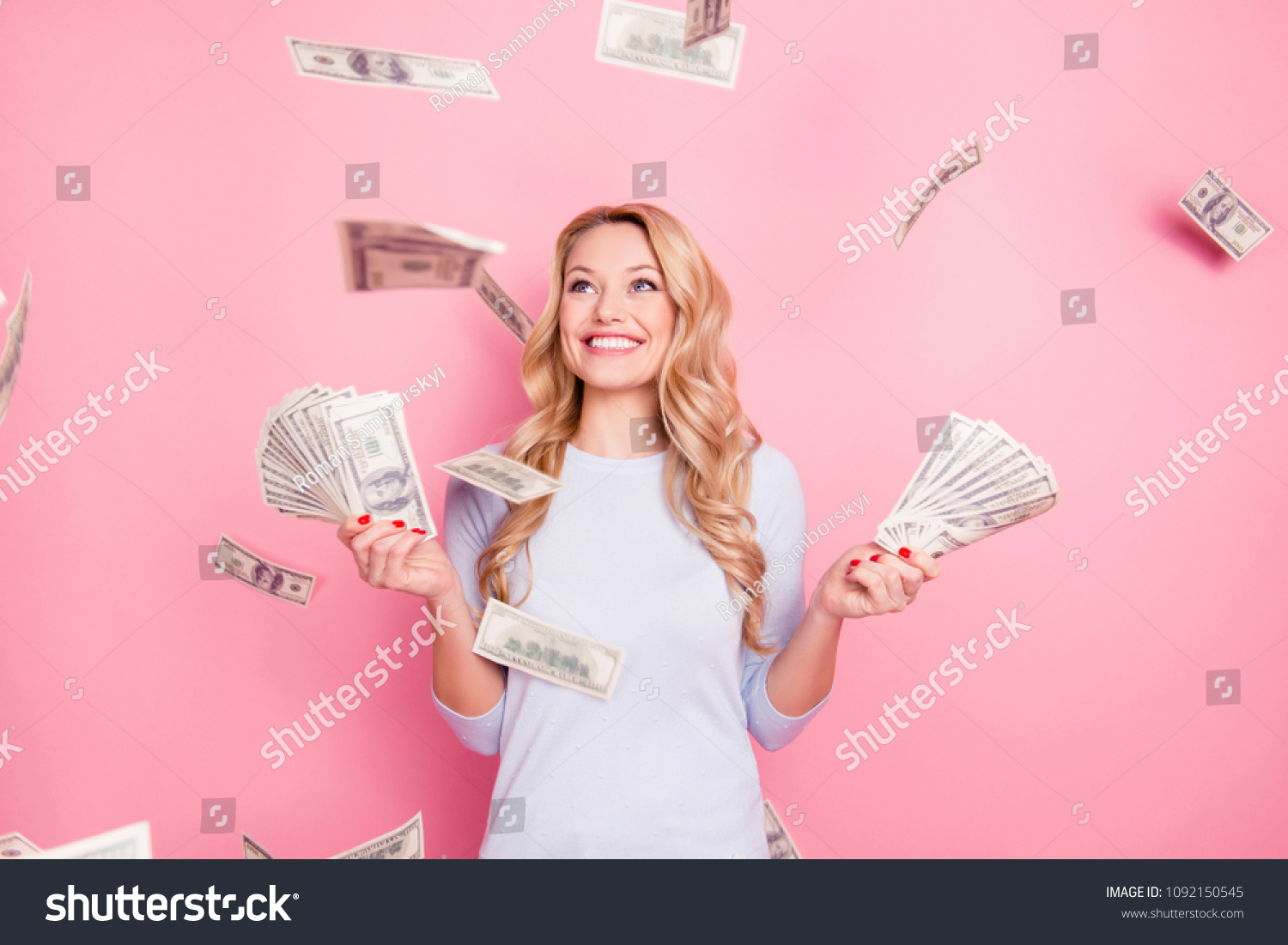 Portrait of pretty charming positive cute successful lucky cheerful girl standing under shower from money having a lot of money in hands isolated on pink background #1092150545