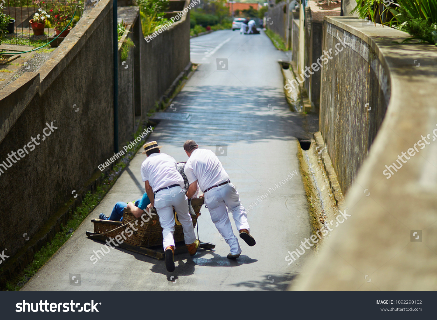 Famous fun tourist activity in Funchal, Madeira island, Portugal. Toboggan riders pushing wooden sledge with tourists downhill with high speed #1092290102