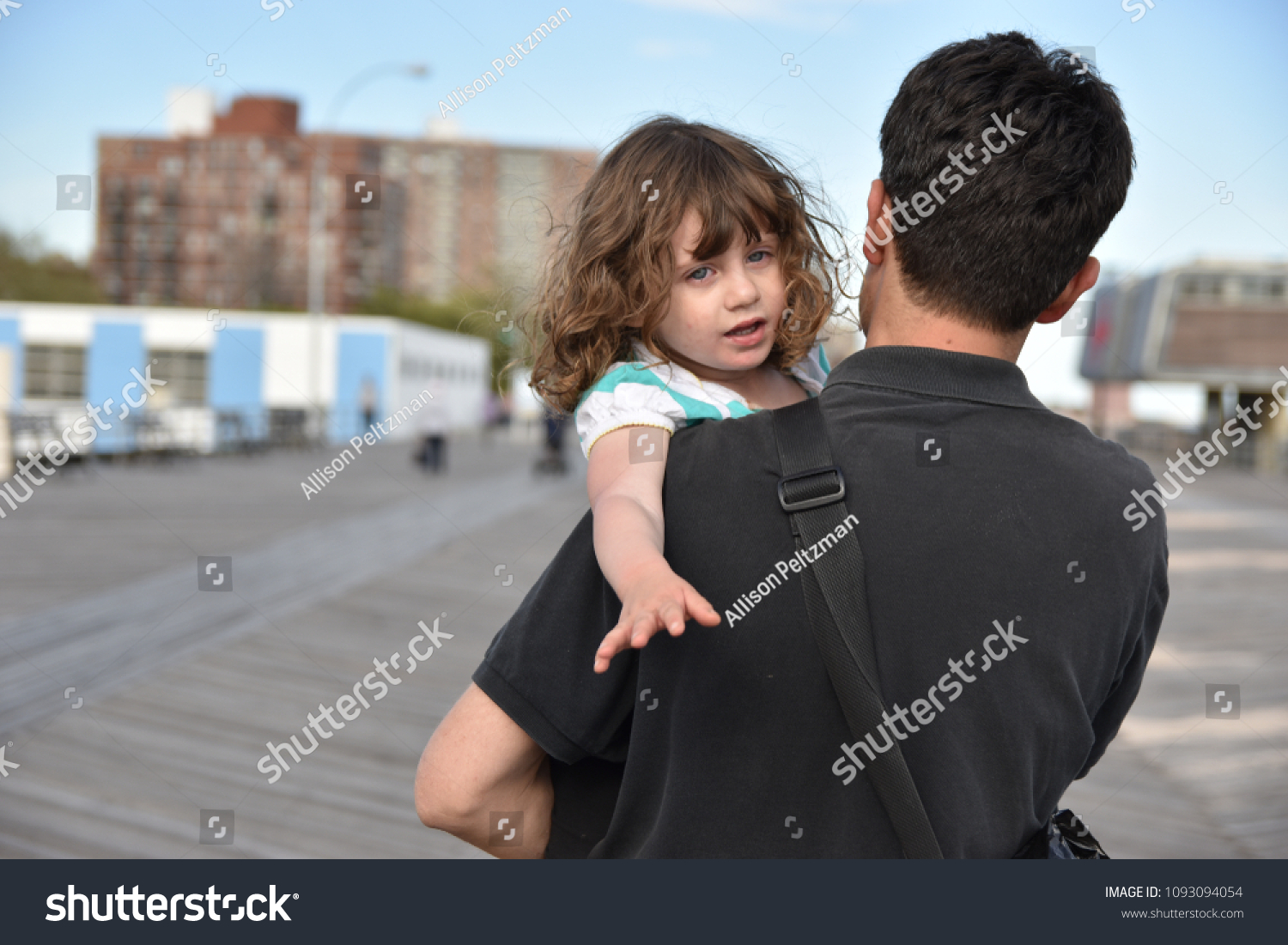 Little girl in her dad’s arms reaches out with yearning for something unattainable #1093094054