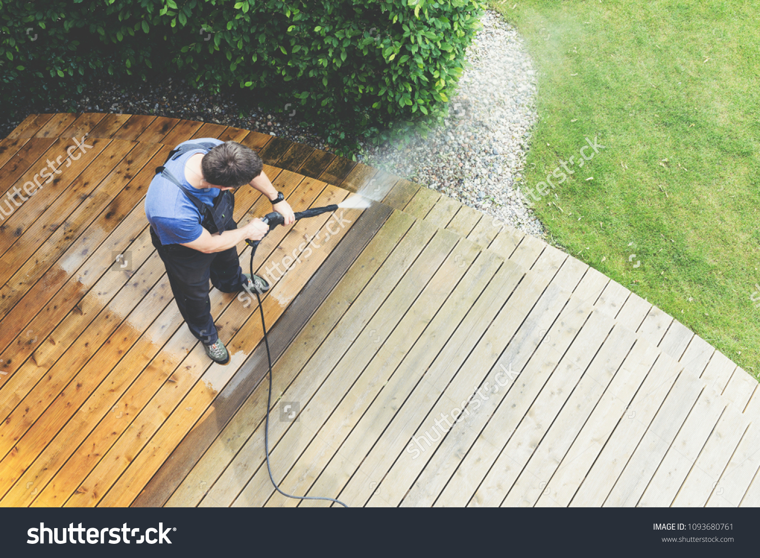 man cleaning terrace with a power washer - high water pressure cleaner on wooden terrace surface #1093680761