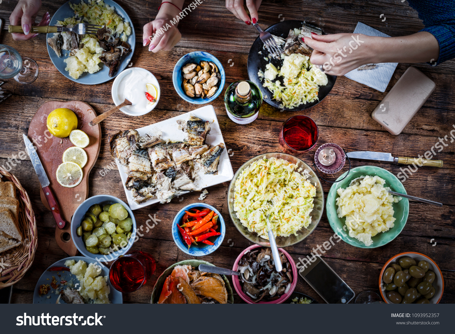 Flat-lay of friends hands eating and drinking together.Food Catering.Buffet Party Concept.having party, gathering,celebrating together at wooden rustic table set with different wine snacks. top view #1093952357