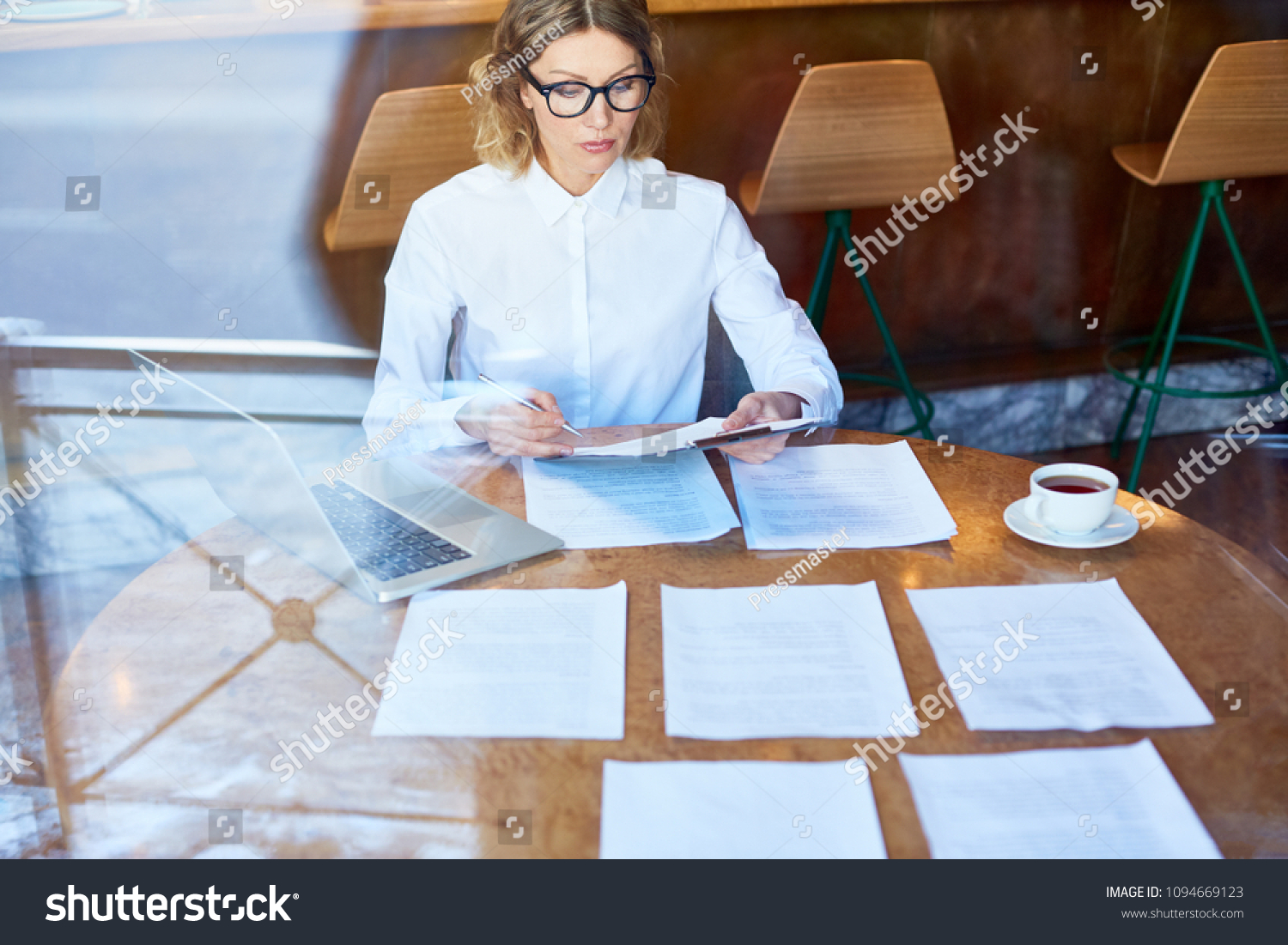 Young businesswoman concentrating on reading texts of new contracts and notifying their main points #1094669123