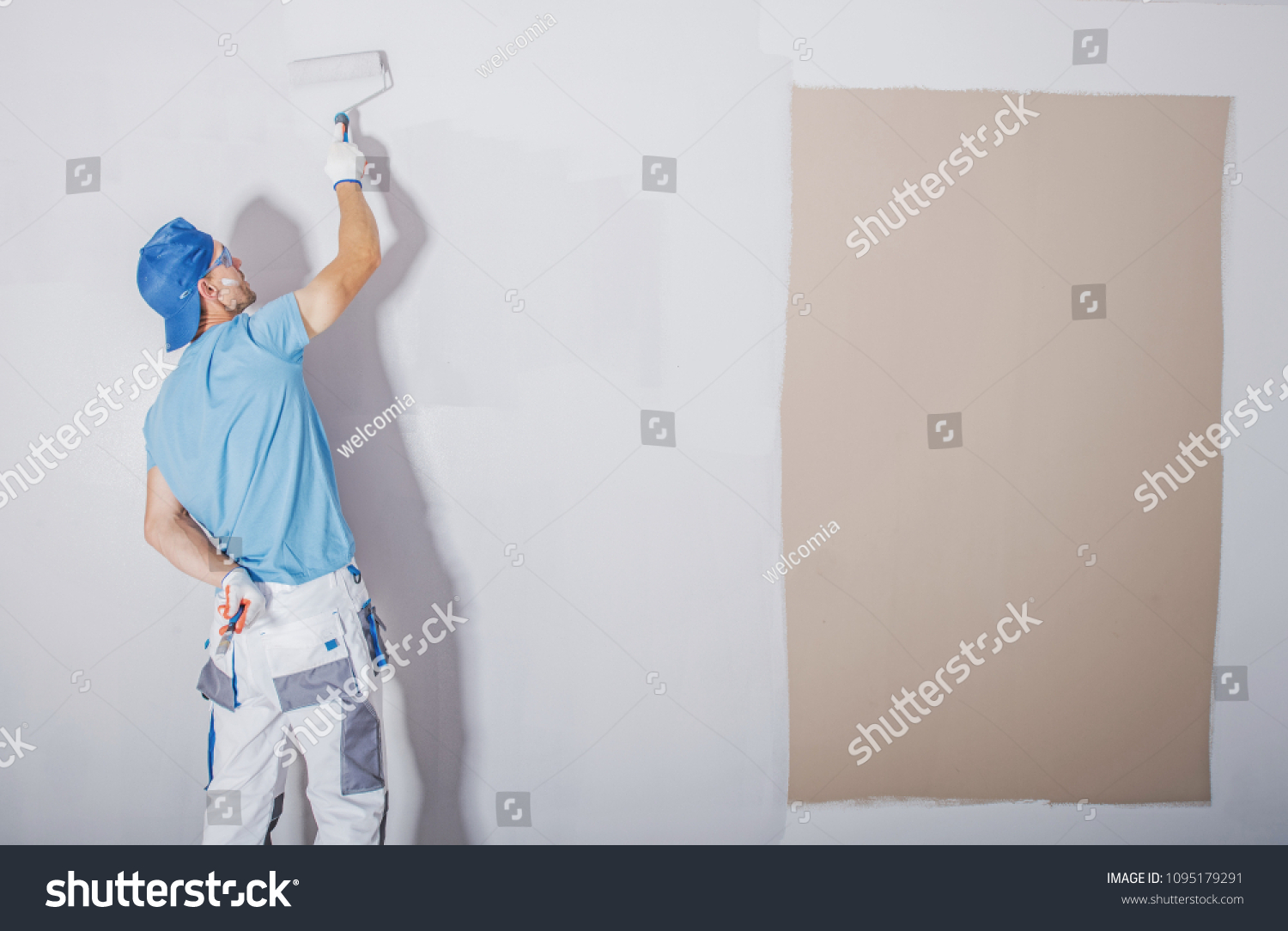 Room Painter at Work. Covering Darker Paint by Fresh and Lighter One. Apartment Renovation. Refreshing the Walls. Construction Theme. #1095179291