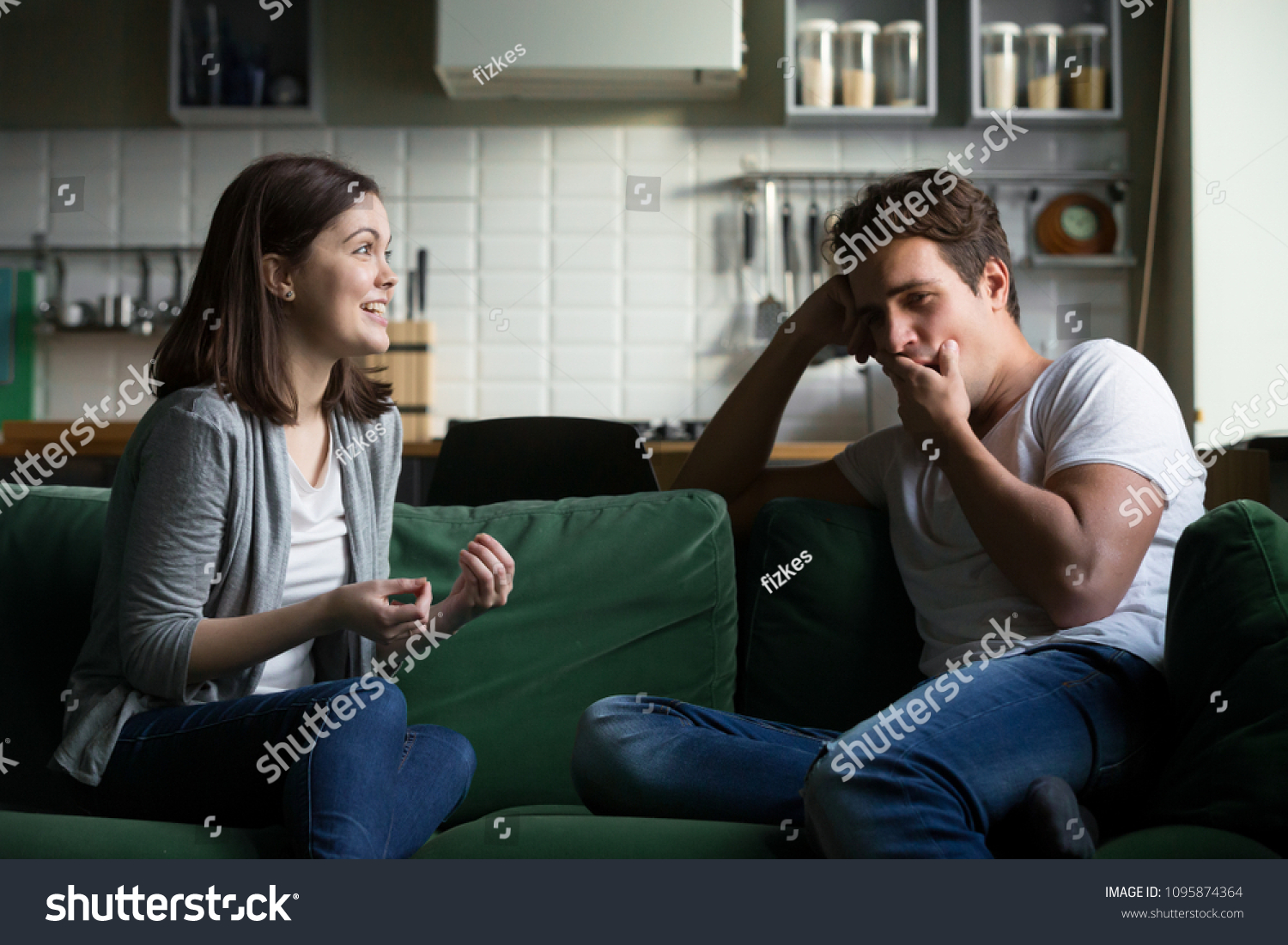 Young husband yawning getting bored listening to excited wife talking for a long time, tired boyfriend not interested in girlfriend gossiping sitting on couch at home, boring conversation concept #1095874364