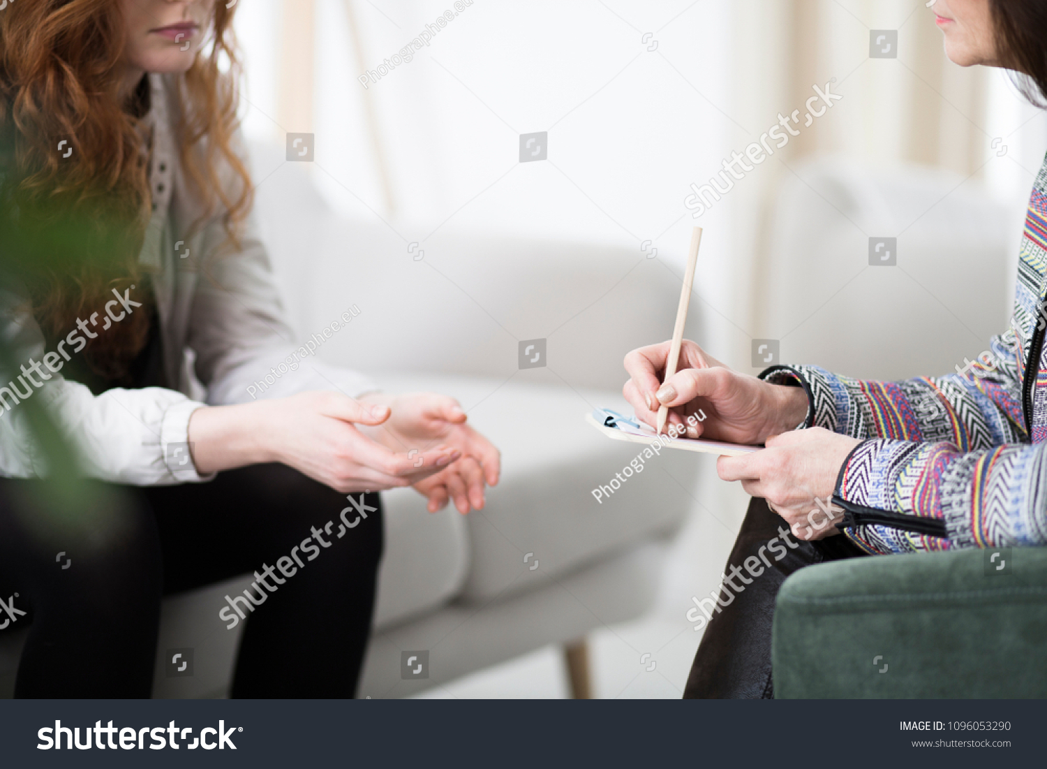 Cropped photo of a therapist writing down notes during therapy with her female patient #1096053290