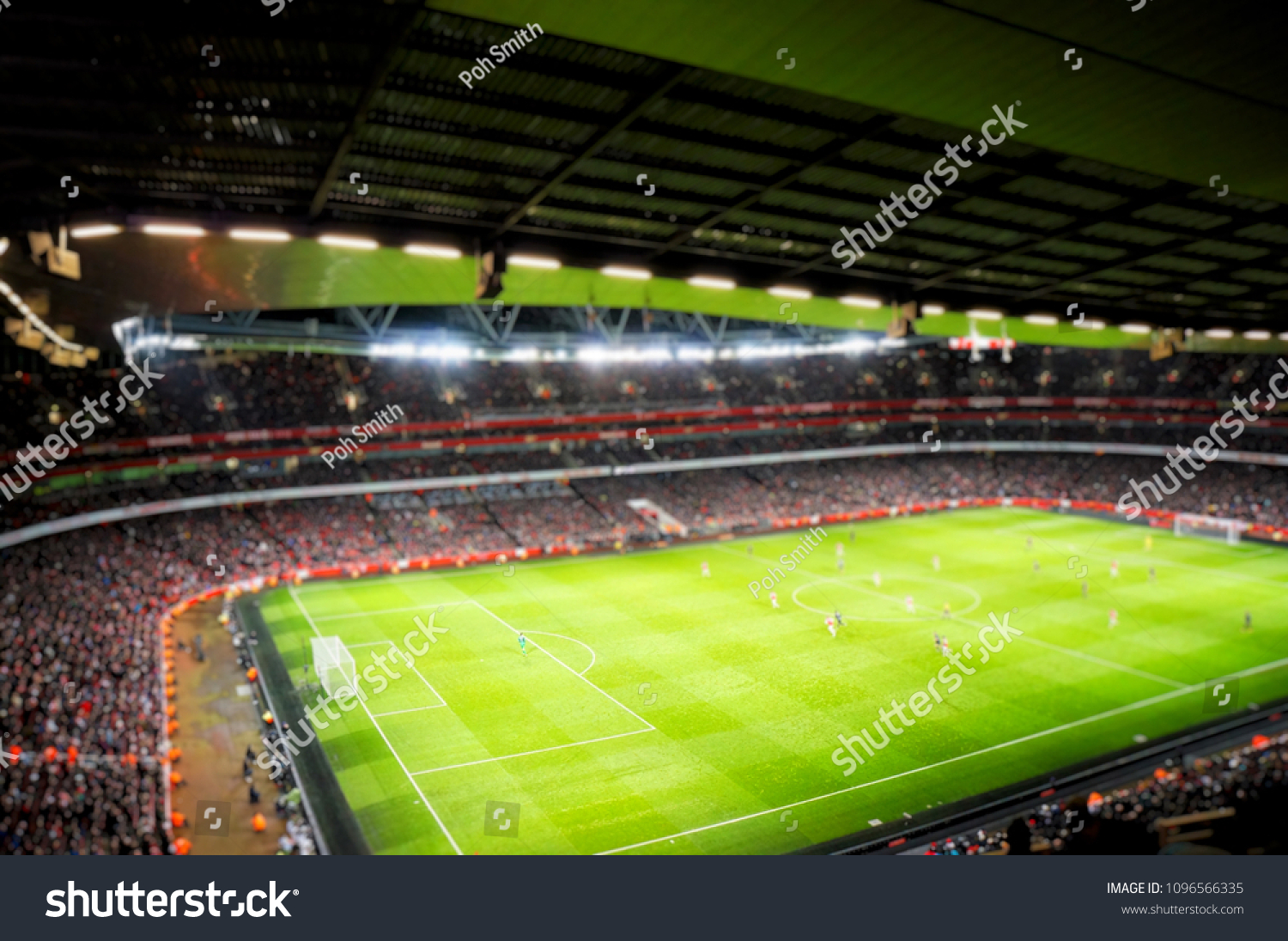 Blurred background of football players playing and soccer fans in match day on beautiful green field with sport light at the stadium.Sports,Athlete,People Concept.Arsenal,Emirates Stadium. #1096566335