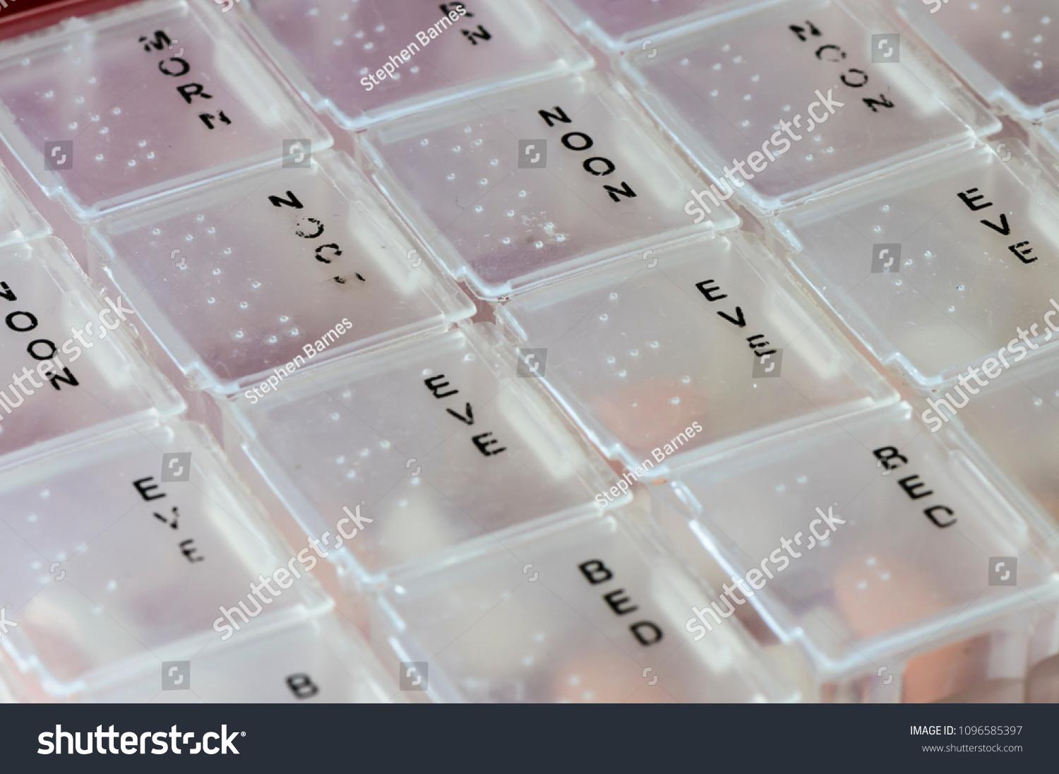 Close up of a segmented pill box for morning, noon, evening and bedtime medications with braille. #1096585397
