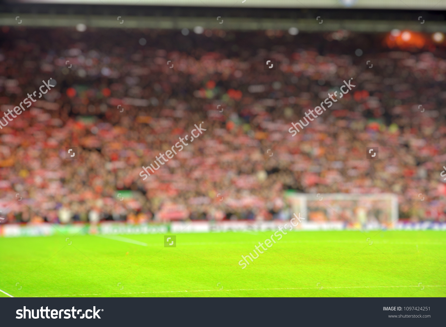 Blurred background of football stadium and soccer fans in match day on beautiful green field with sport light at the stadium.Sports,Athlete,People Concept.Anfield,Liverpool #1097424251