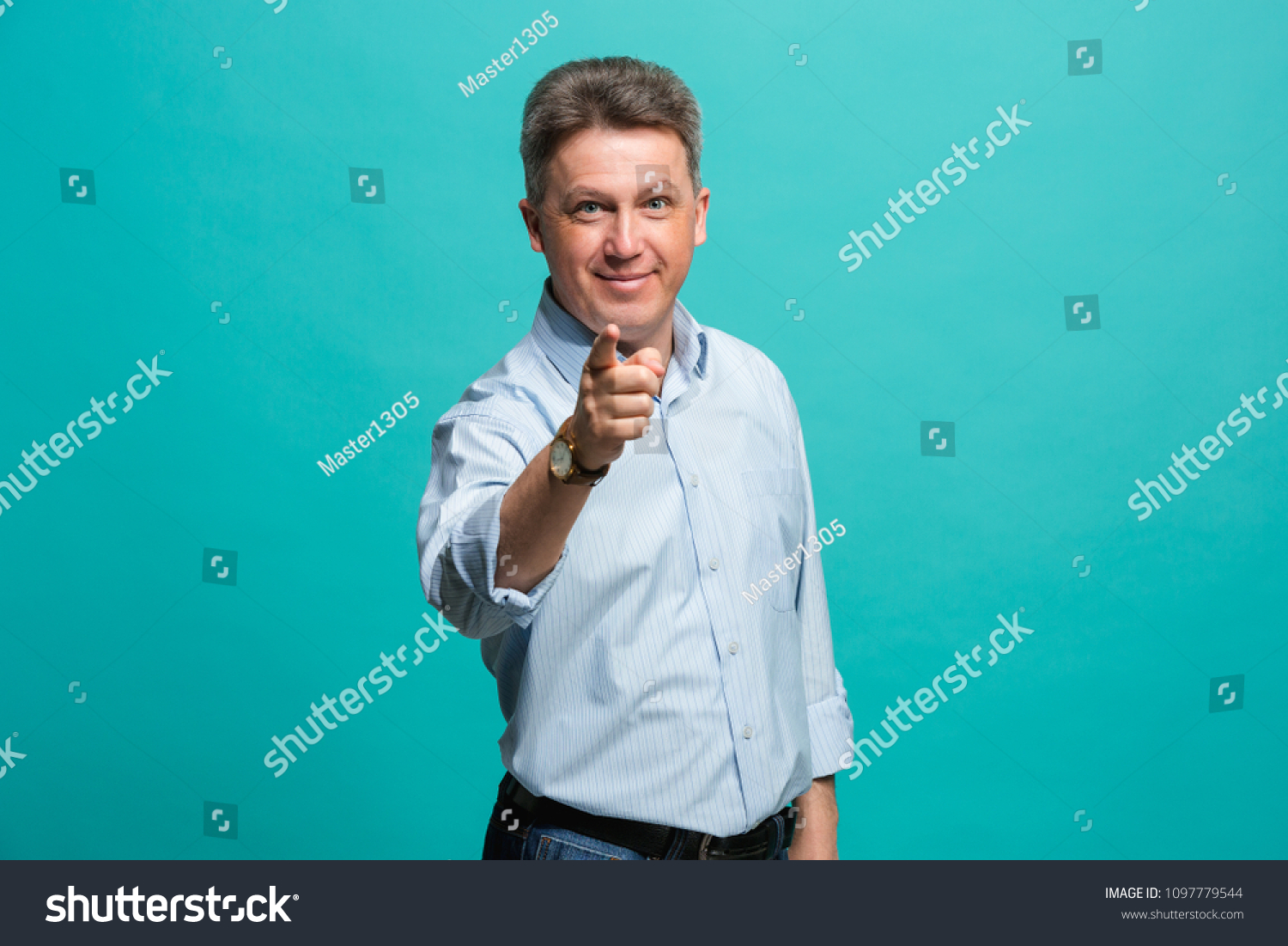 I choose you and order. The smiling business man point you, want you, half length closeup portrait on blue studio background. The human emotions, facial expression concept. Front view. Trendy colors #1097779544