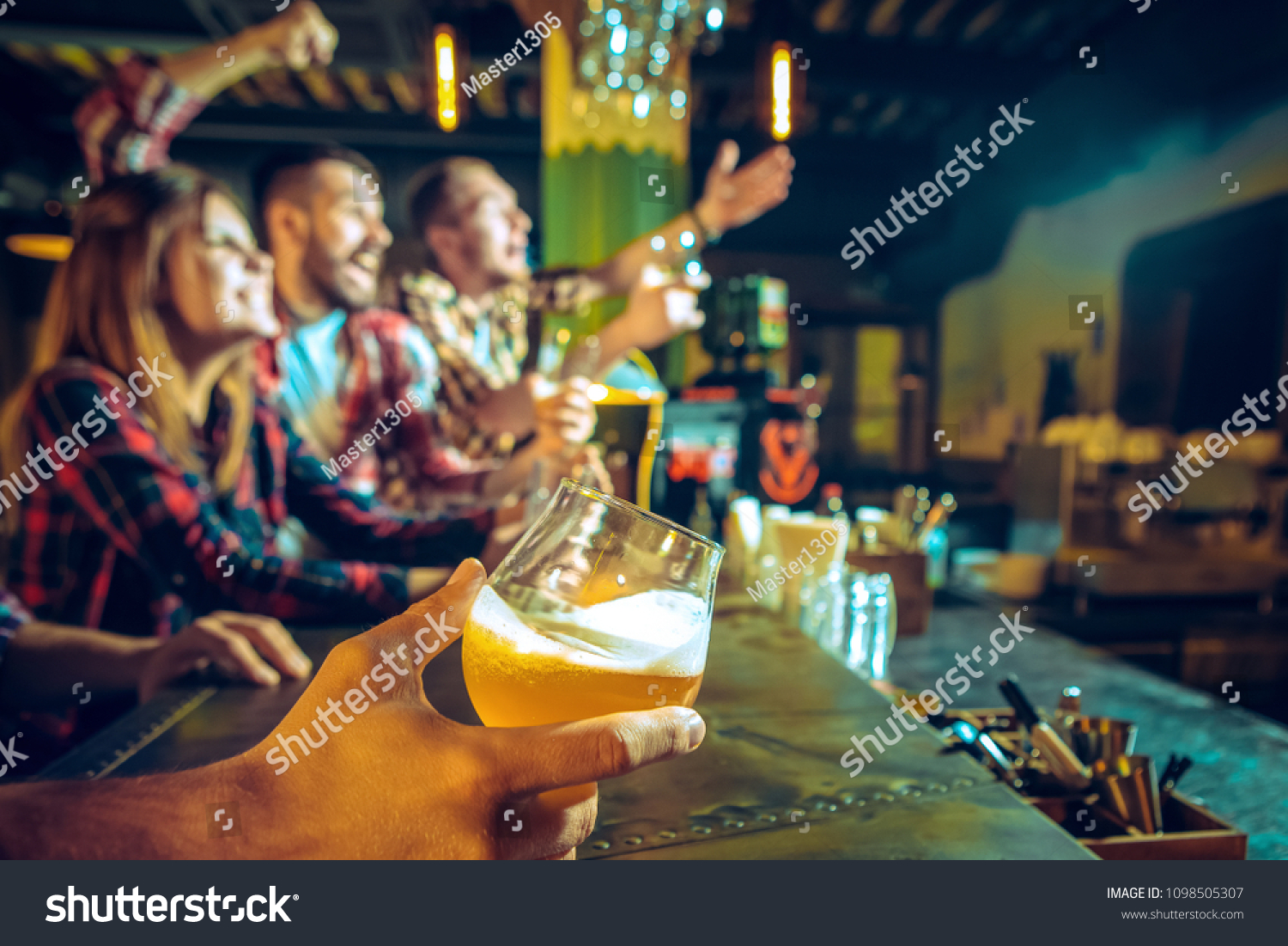 Sport, people, leisure, friendship, entertainment concept - happy male and female football fans or good yuong friends drinking beer, celebrating victory at bar or pub. Human positive emotions concept #1098505307