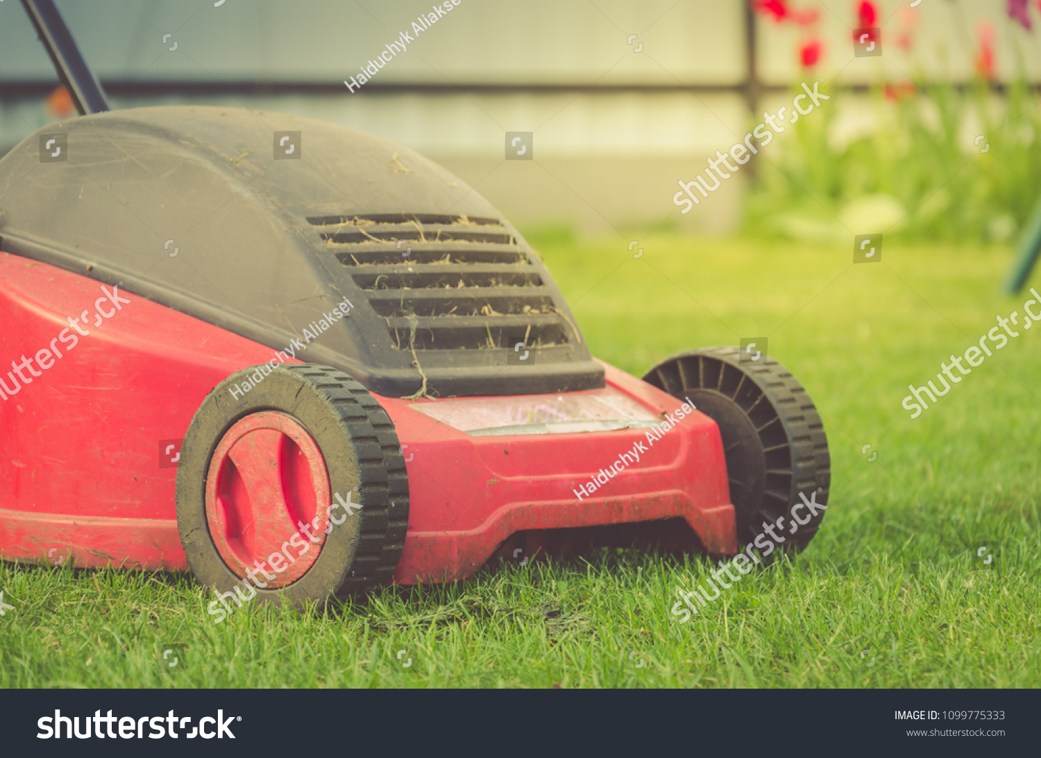 lawn mower on the lawn/red lawn mower on summer meadow. Selective focus #1099775333
