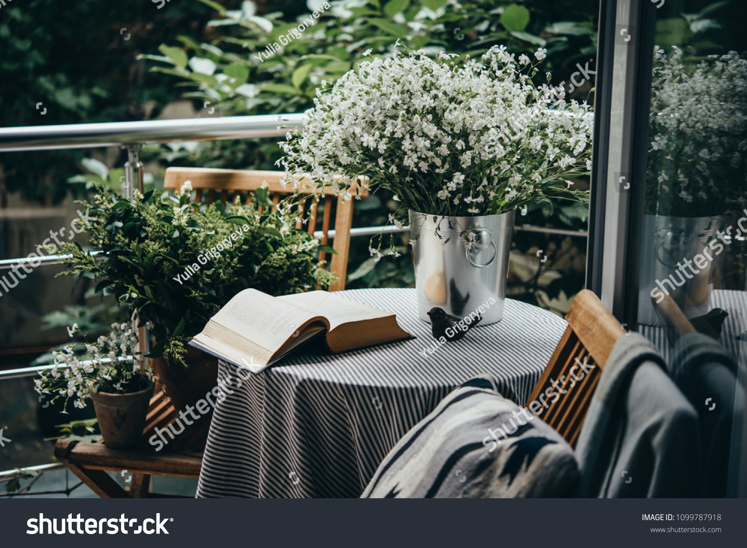 Small table, book and flowers on a beautiful terrace or balcony #1099787918