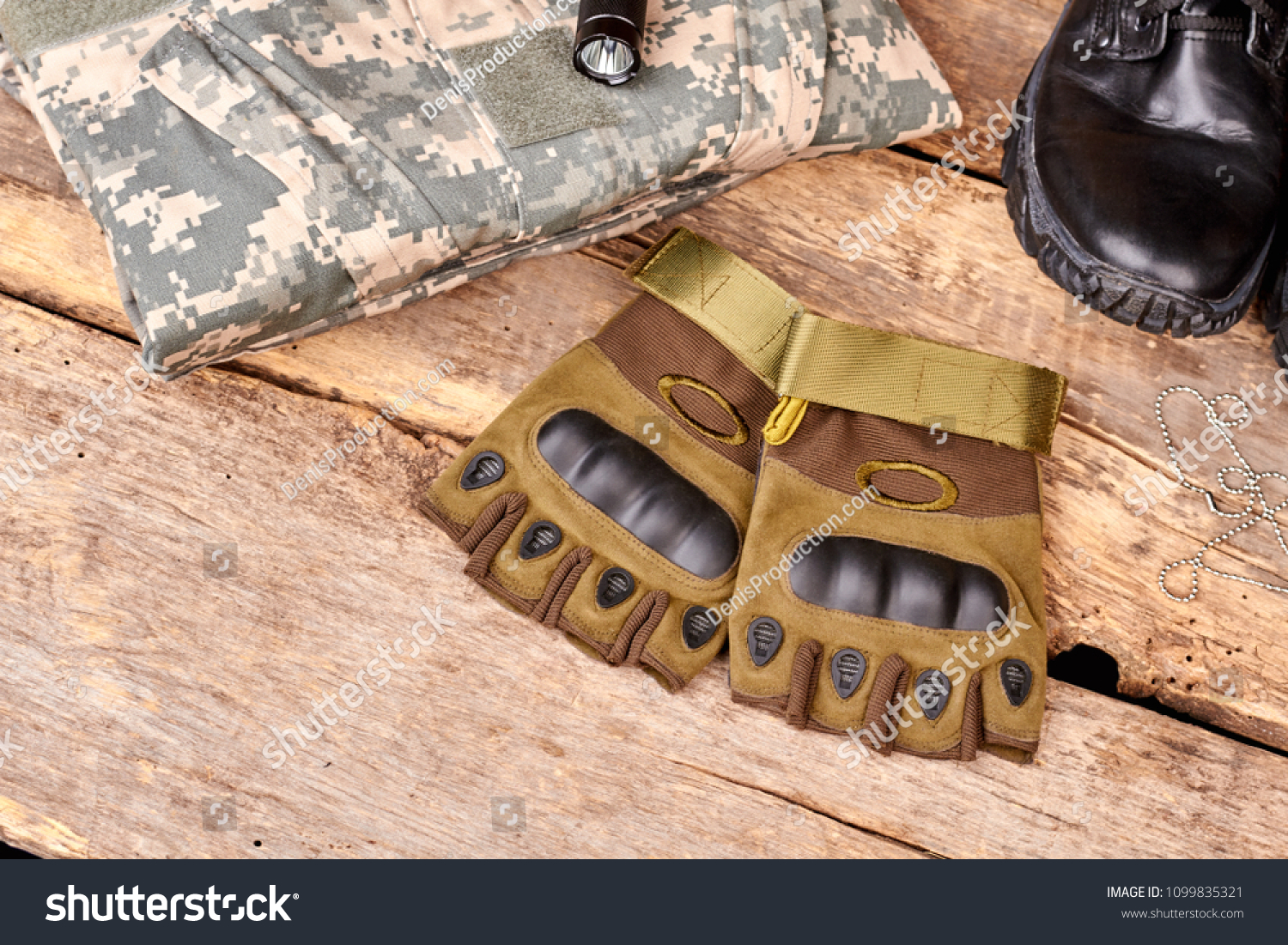 Pair of fingerless gloves and camouflage clothes on wood. Black shoe and torch. Flat lay, top view. #1099835321