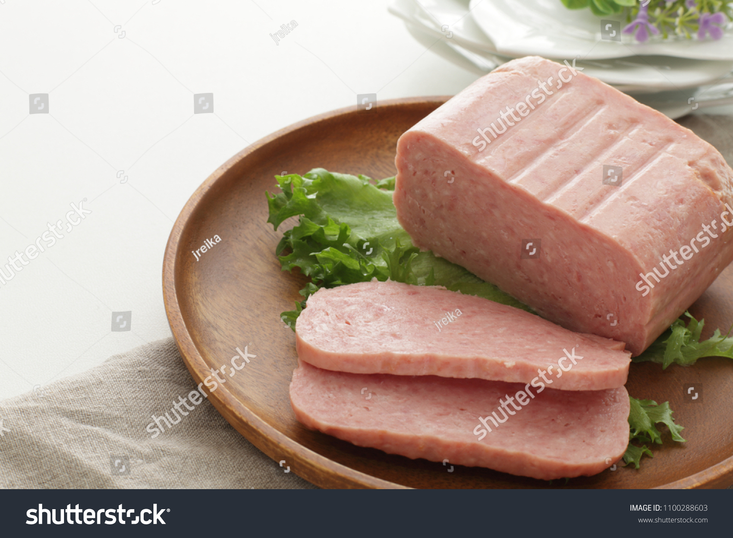 Sliced luncheon meat on wooden plate #1100288603