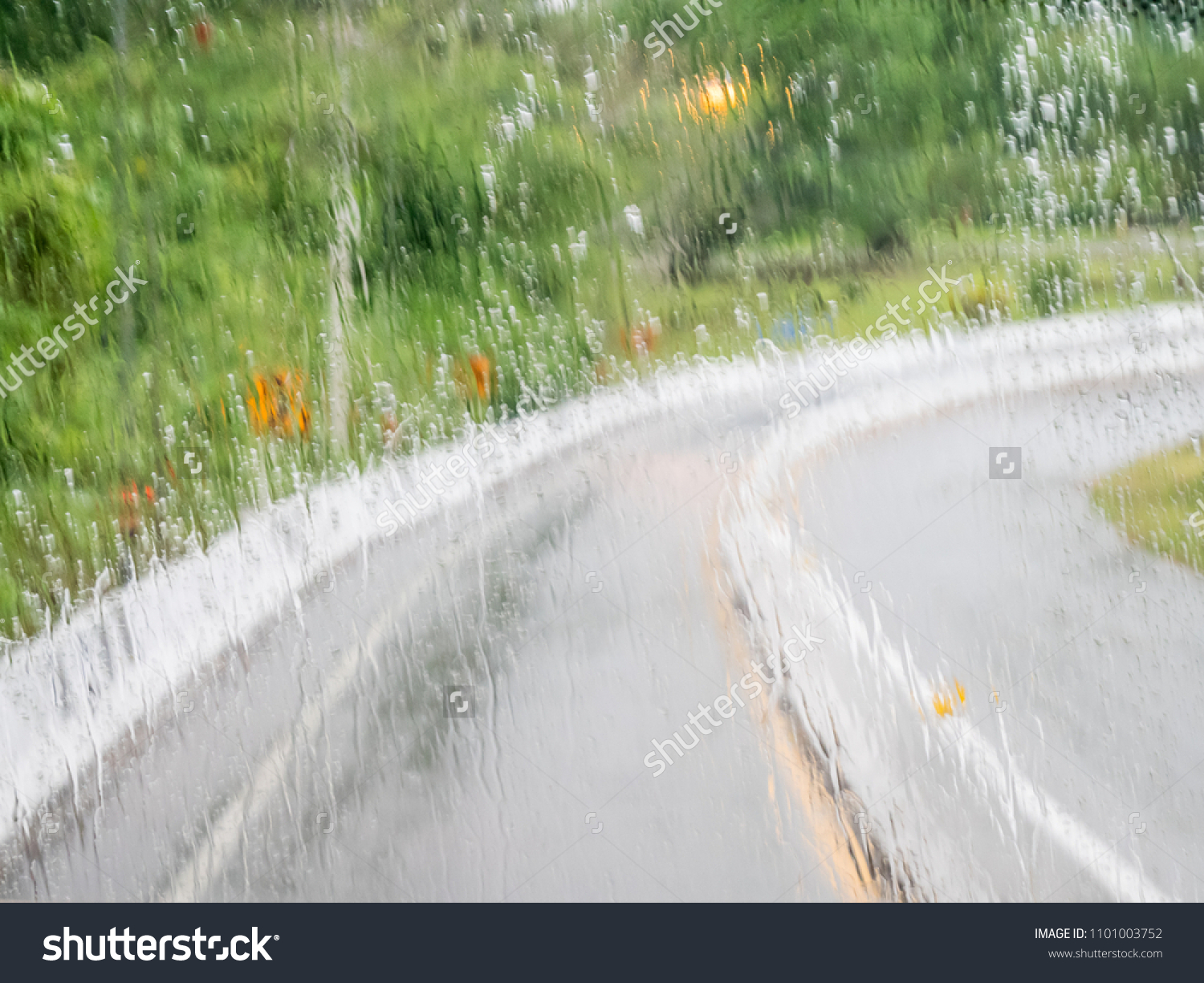 Blurred of wetting glass in front of a moving car on slipping curve road or street in rainy day can use for warning photo to be careful when driving the vehicle in raining season. #1101003752