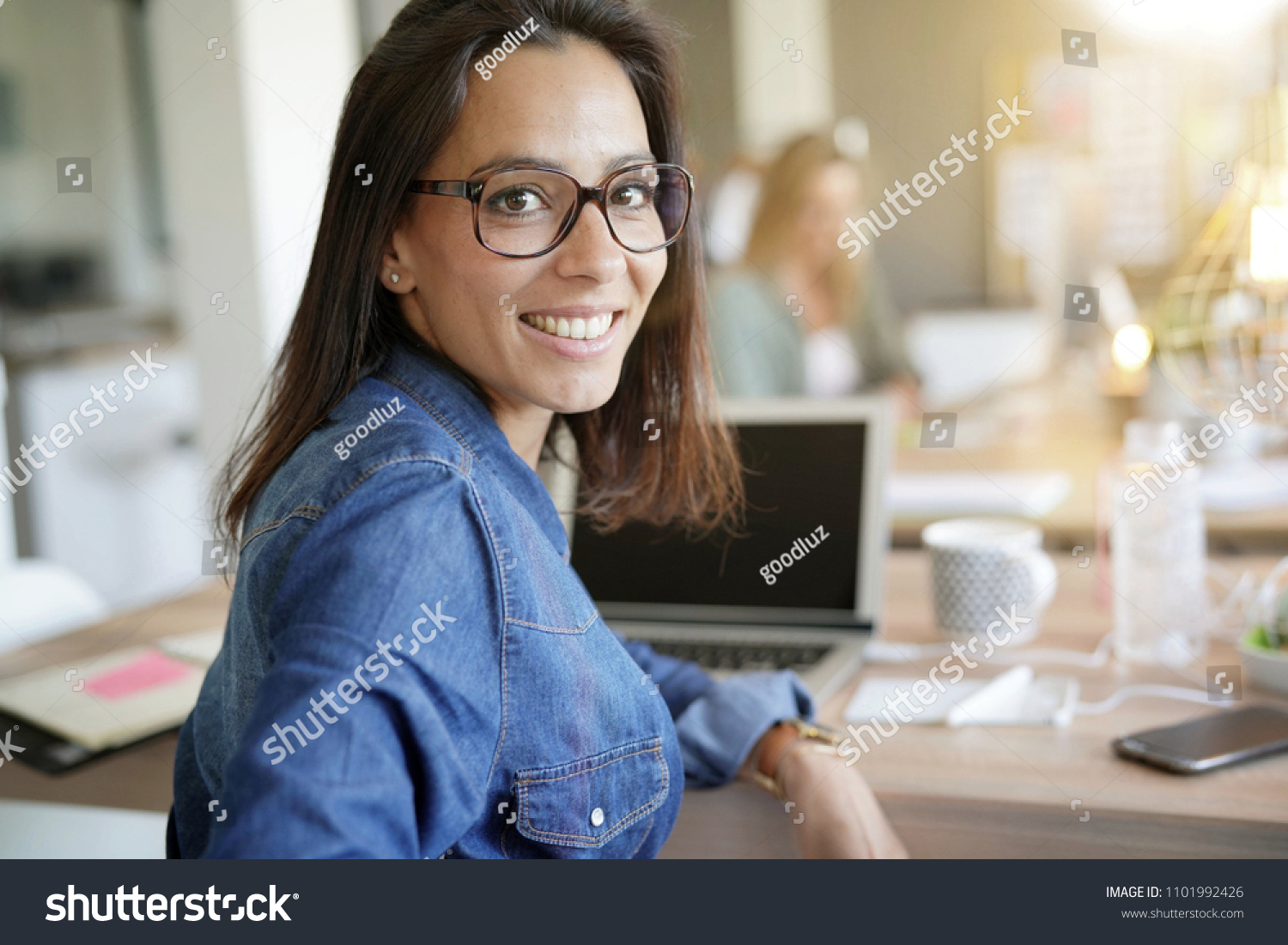 Cheerful girl working in co-working office #1101992426