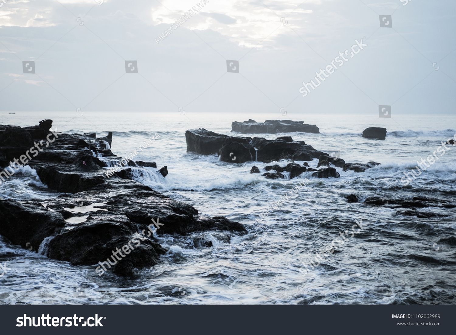 the waves of the ocean are breaking against the rocks. splashing ocean waves at sunset. #1102062989