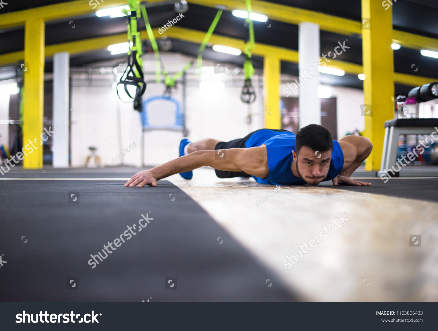 Young strong man doing pushups  at cross fitness gym #1103806433
