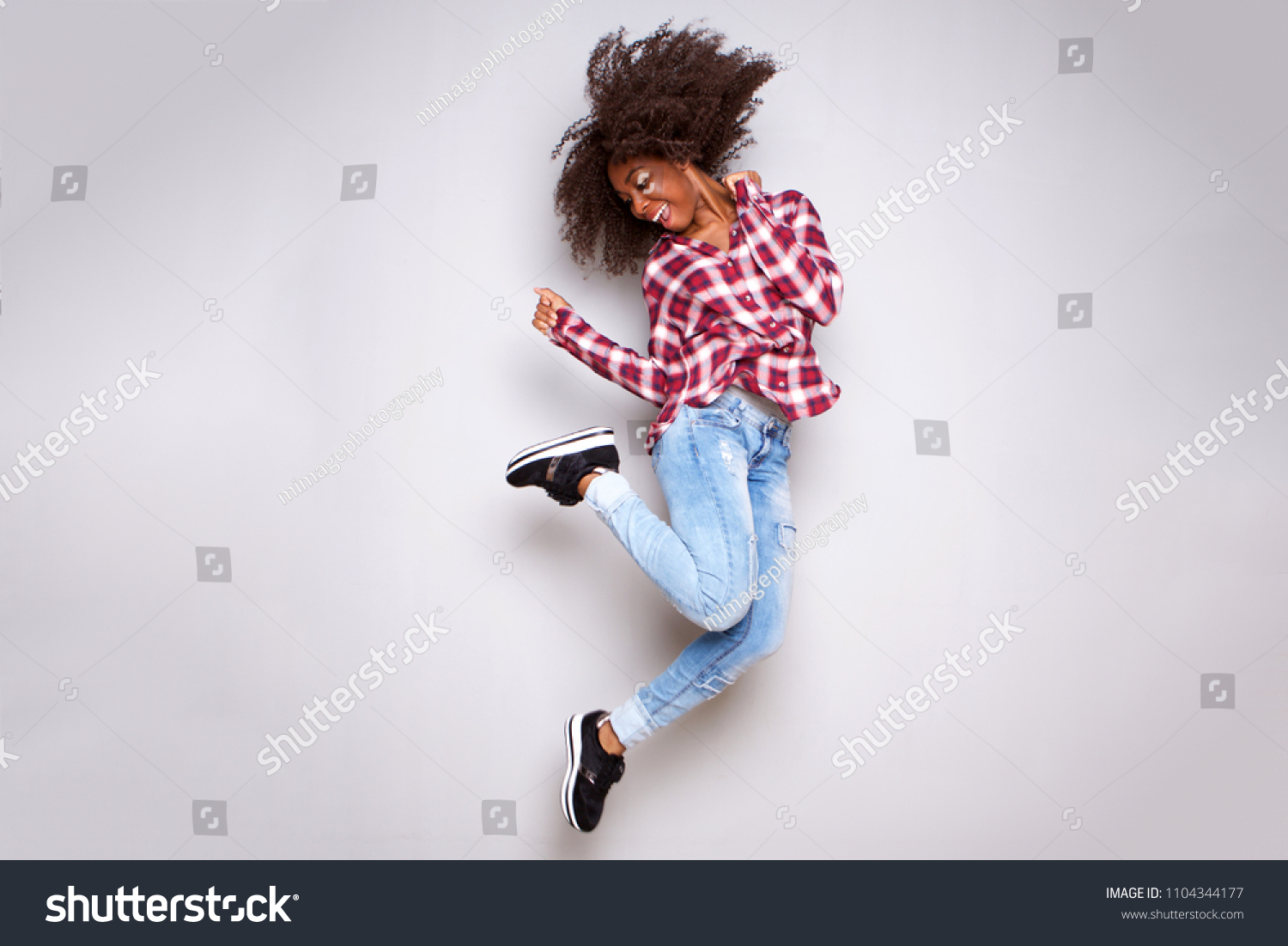 Full body portrait of cheerful young african woman jumping in air over white background #1104344177