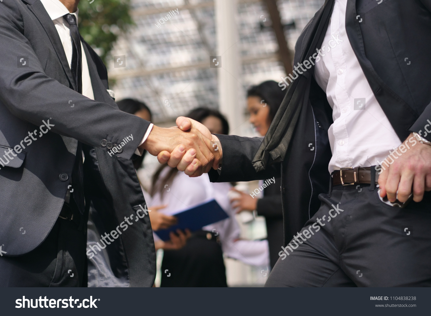 A man and a woman business, of different ethnicities, shake hands and then talk about finance looking at the patterns of economic markets and banks. Concept of: success and team #1104838238