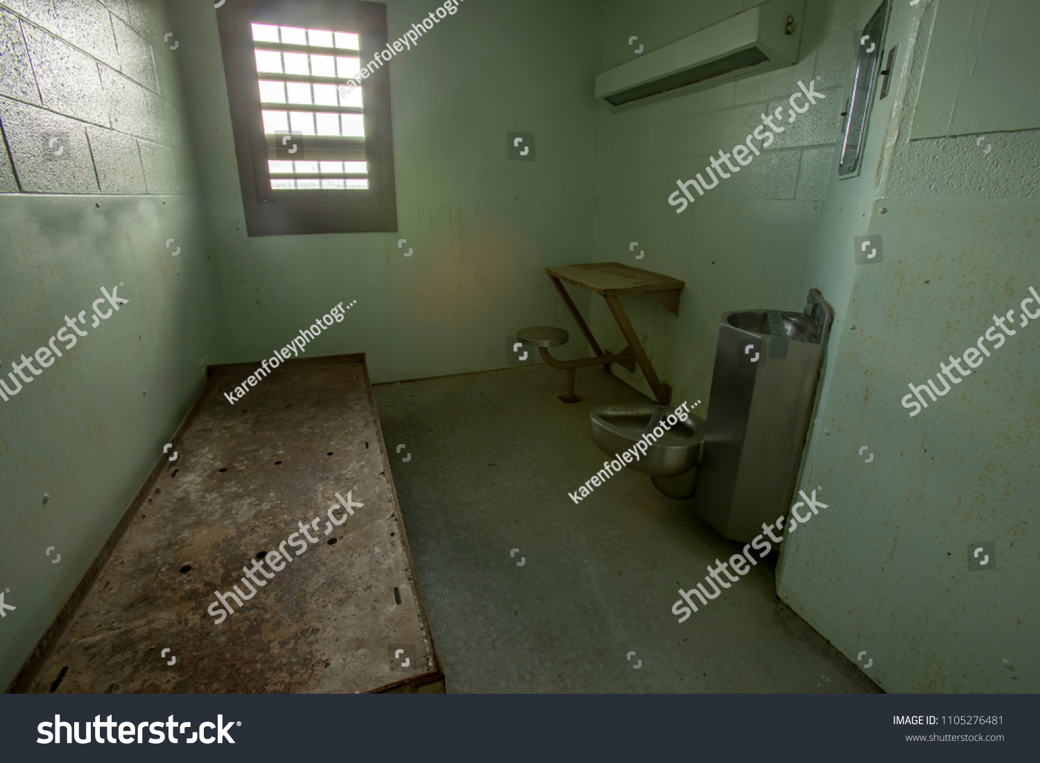 Interior of solitary confinement cell with metal bed, desk and toilet in old prison. #1105276481