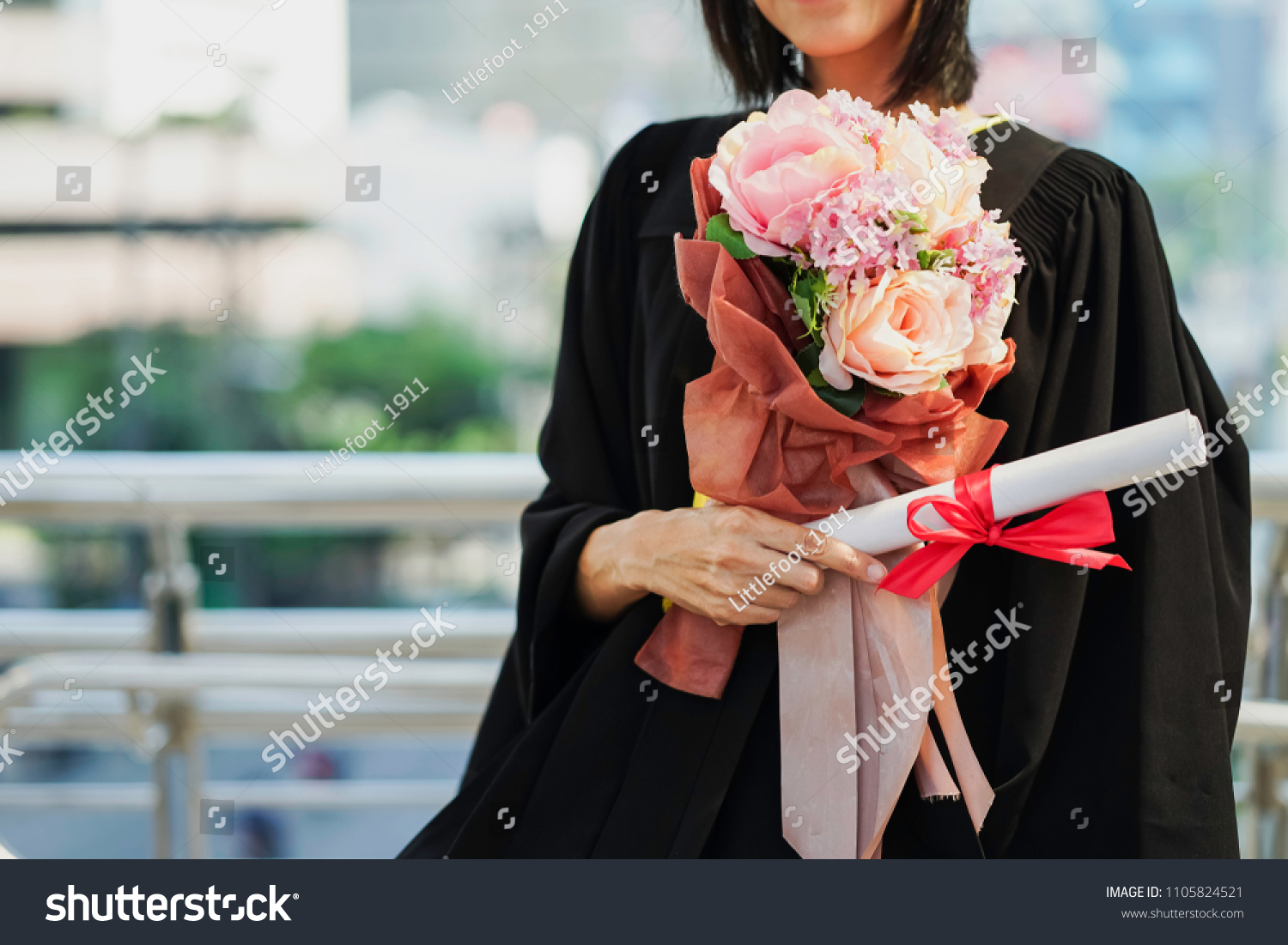 Happiness graduation day concept, woman graduate hand holding diploma and flower bouquet. #1105824521