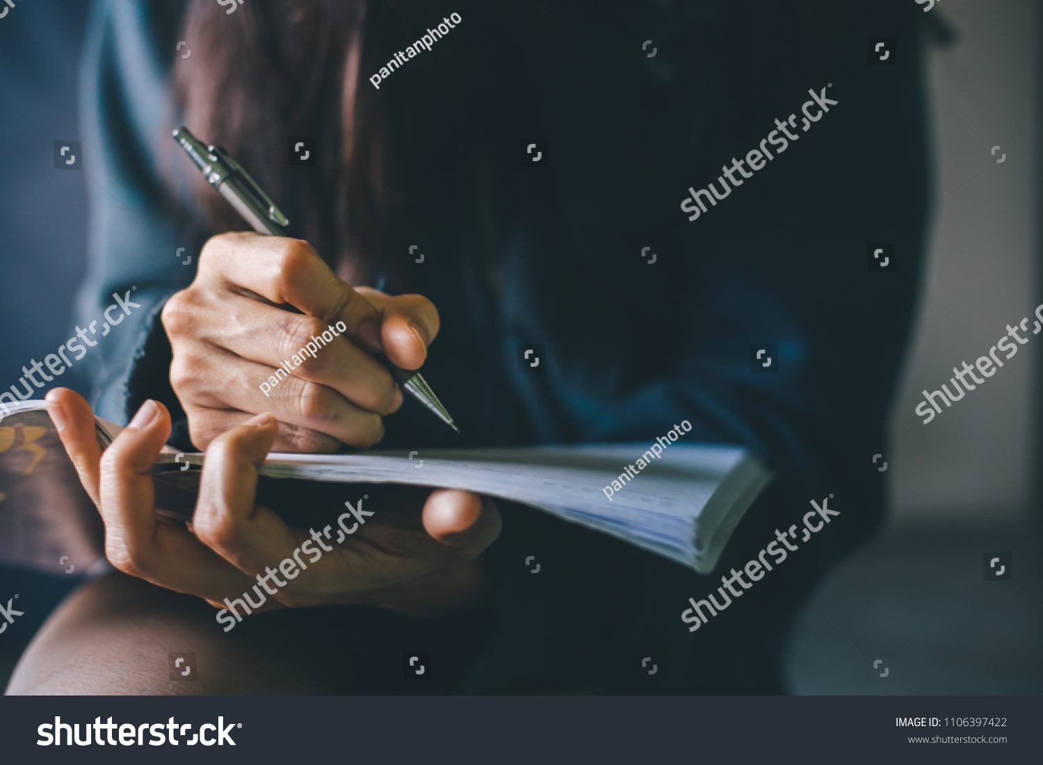 soft focus.hand high school or university student in casual holding pencil writing on paper answer sheet.sitting on lecture chair taking final exam or study attending in examination room or classroom #1106397422