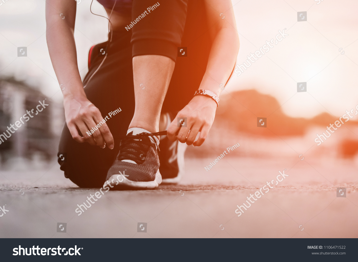 Running shoes - closeup of woman tying shoe laces. Female sport fitness runner getting ready for jogging outdoors on way #1106471522