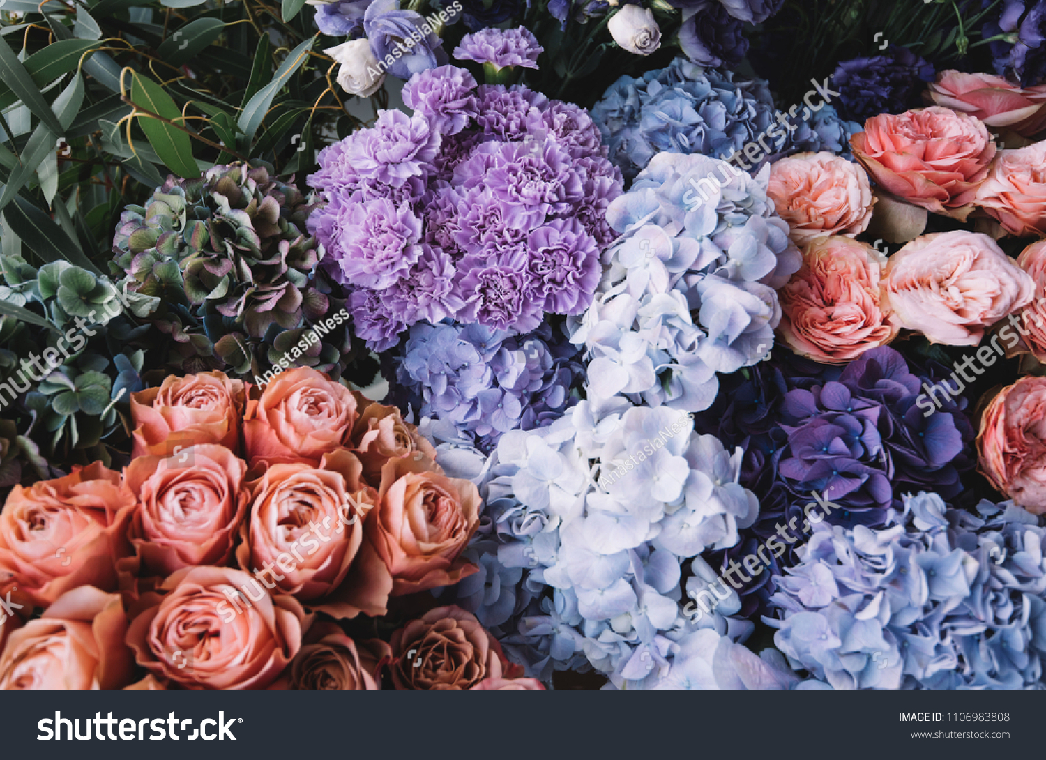 Beautiful blossoming flowers (roses, hydrangeas, carnations, eustoma) in blu, antique blue and peach colours at the florist shop #1106983808