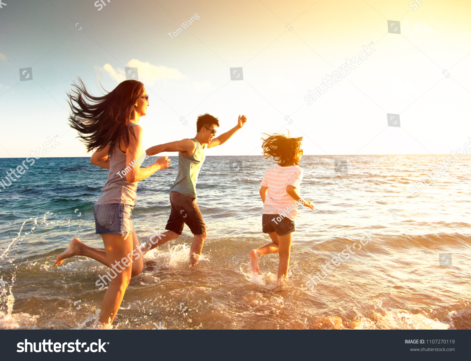 happy family running on the beach #1107270119