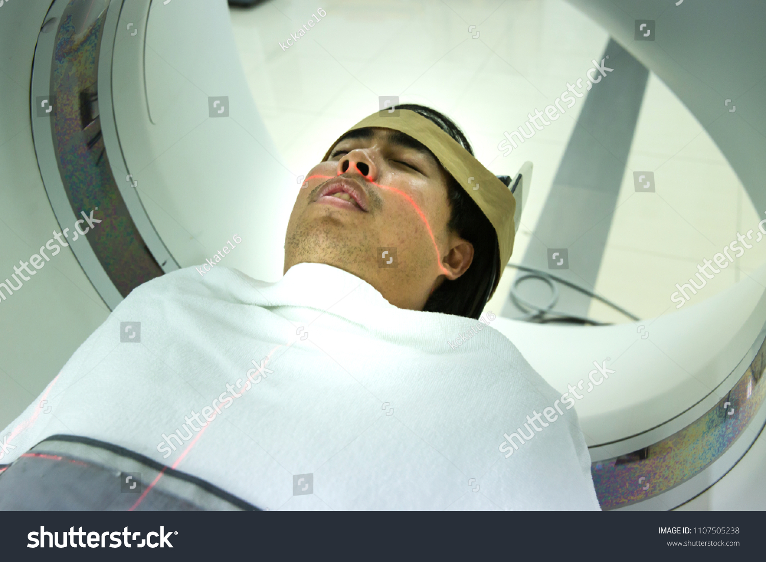 Patients screening on CT scanner. Man Undergoing CT Scan While Doctor's Using Computers. Examining man in CT scanner. Computerised tomography. #1107505238