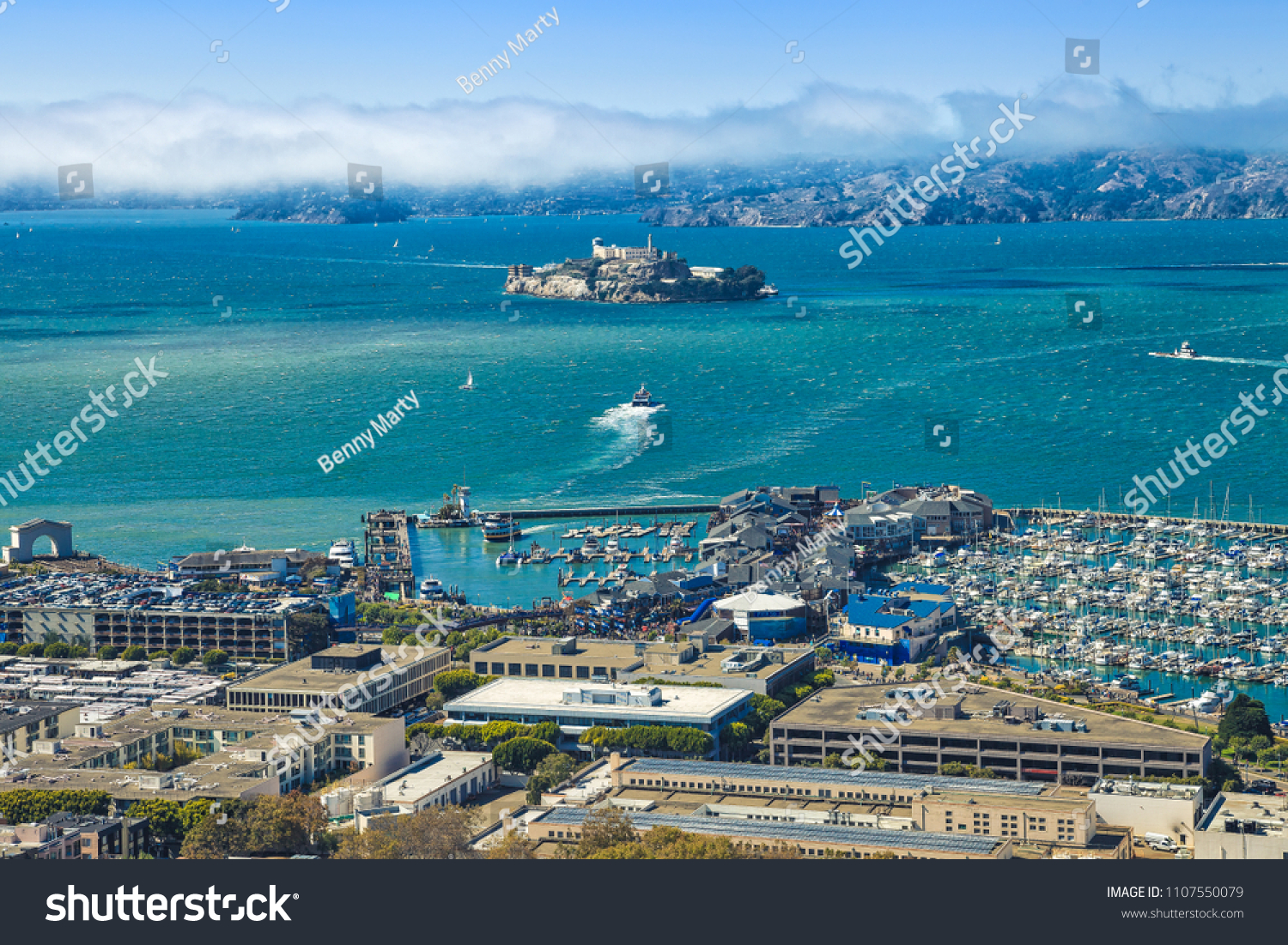 Aerial view of Alcatraz Island, Hyde Street Pier in Fisherman's Wharf and Maritime National Historical Park, from top of Coit Tower on sunny day. San Francisco, California, Unites States. #1107550079