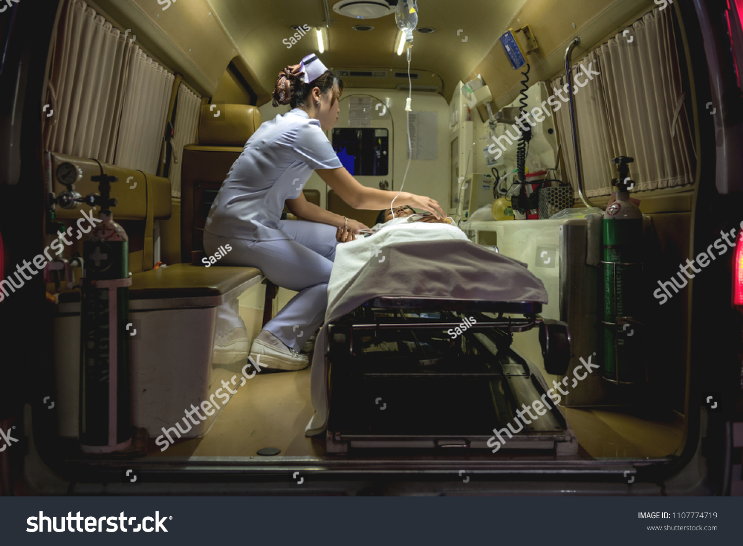 Nurse with patient. Young chinese nurse with her emergency patient in ambulence taking care of her patient. Real ambulence in hospital. Medical concept. #1107774719