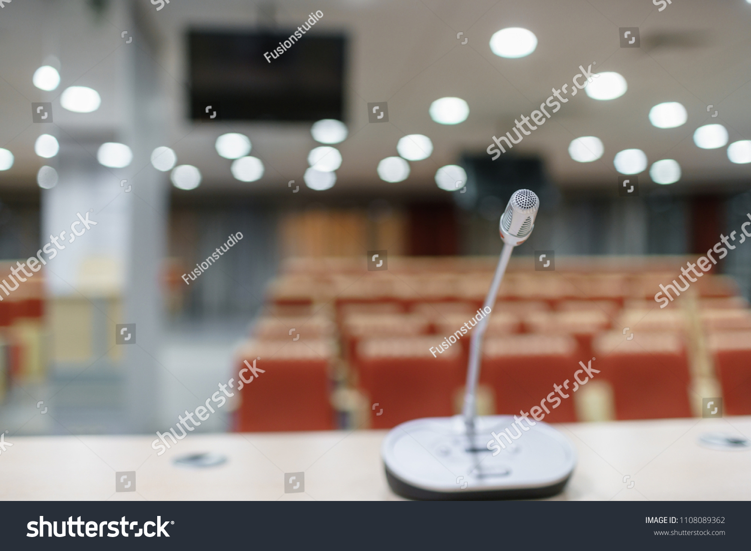 microphone in the foreground. Seminar presentation. Conference room full of empty seats. Red color. Hall for workshops and seminars #1108089362