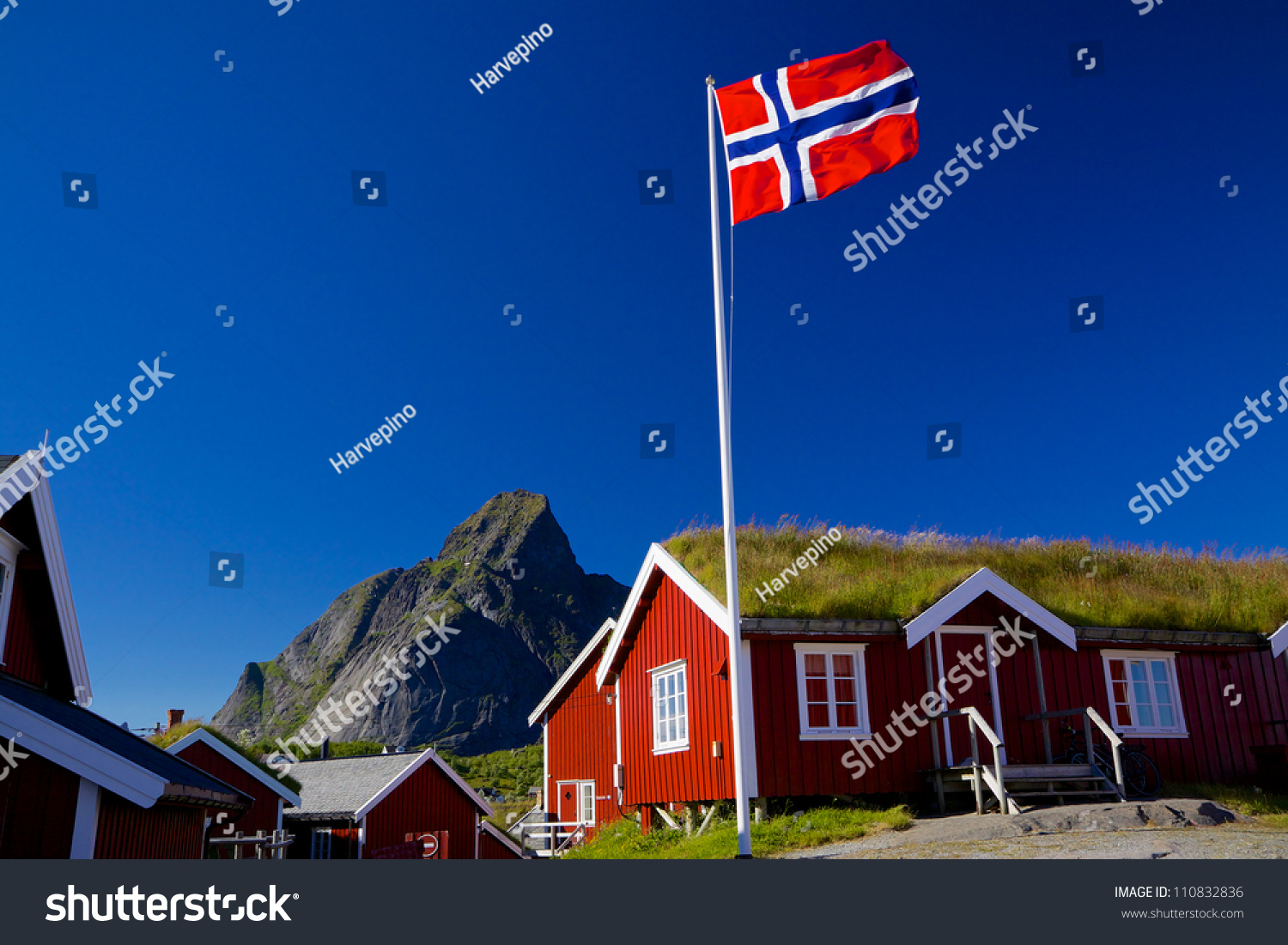 Norwegian flag with typical norwegian red wooden house with sod roof on Lofoten islands #110832836
