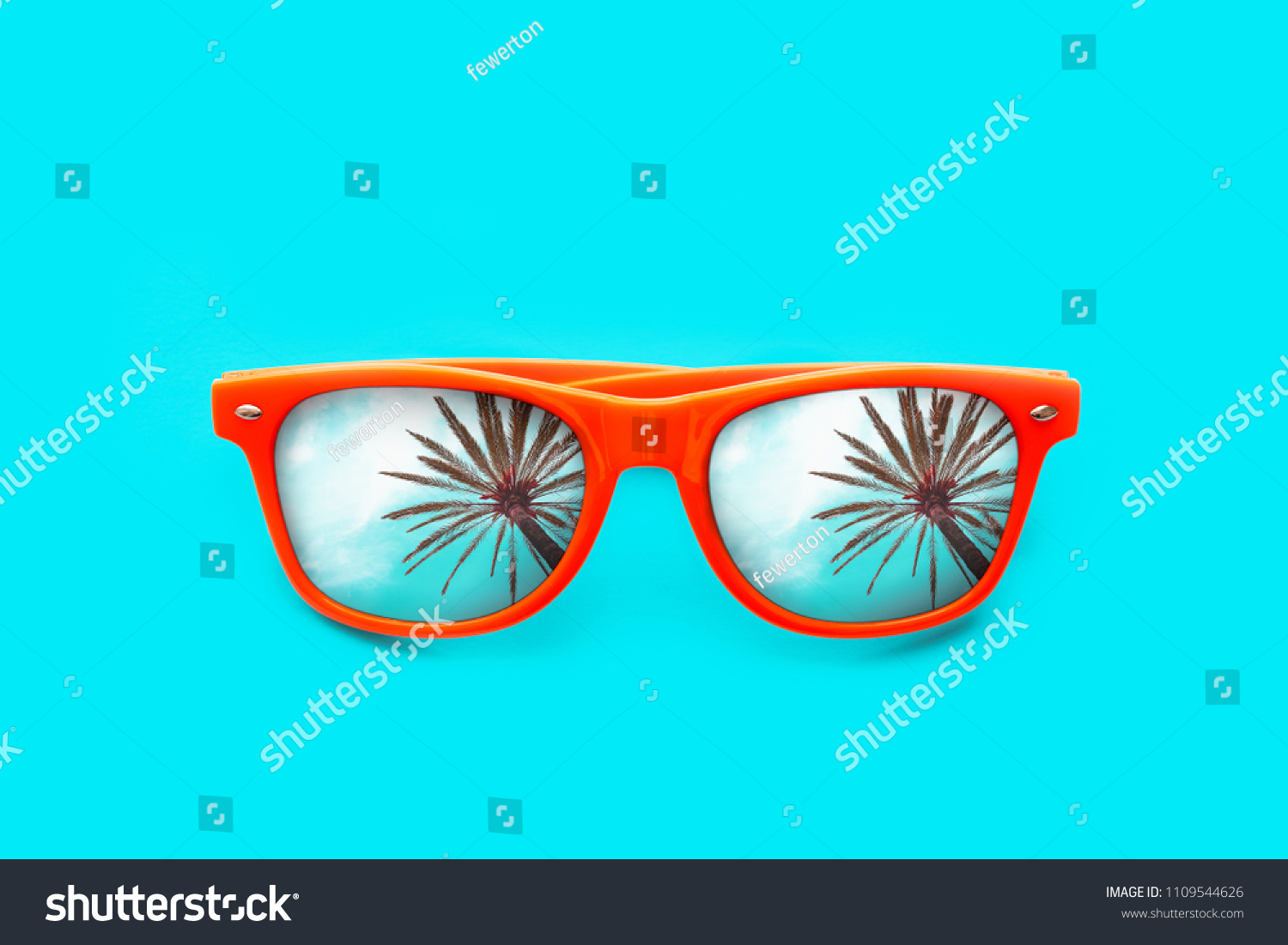 Orange sunglasses with palm tree reflections isolated in intense cyan blue background. Minimal image concept for ready for summer, sun protection, hot days and tropical travel vacation. #1109544626