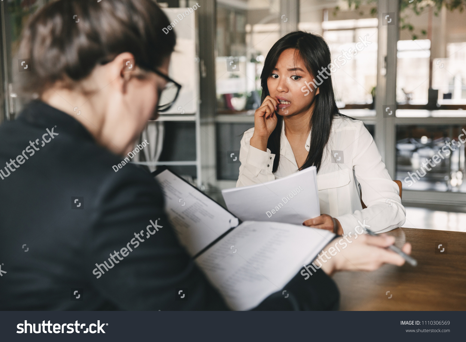 Photo from back of businesswoman interviewing and reading resume of nervous female applicant during job interview - business, career and placement concept #1110306569