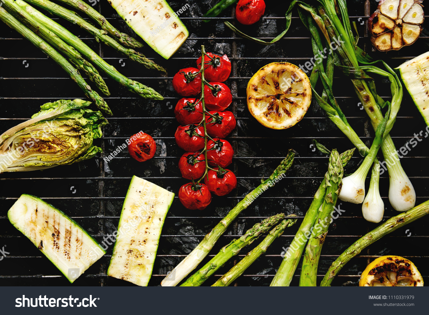Grilled vegetables green asparagus, garlic, lemon, spring onion, zucchini, cherry tomatoes, salad on bbq grill rack over charcoal. Top view. Barbecue concept #1110331979