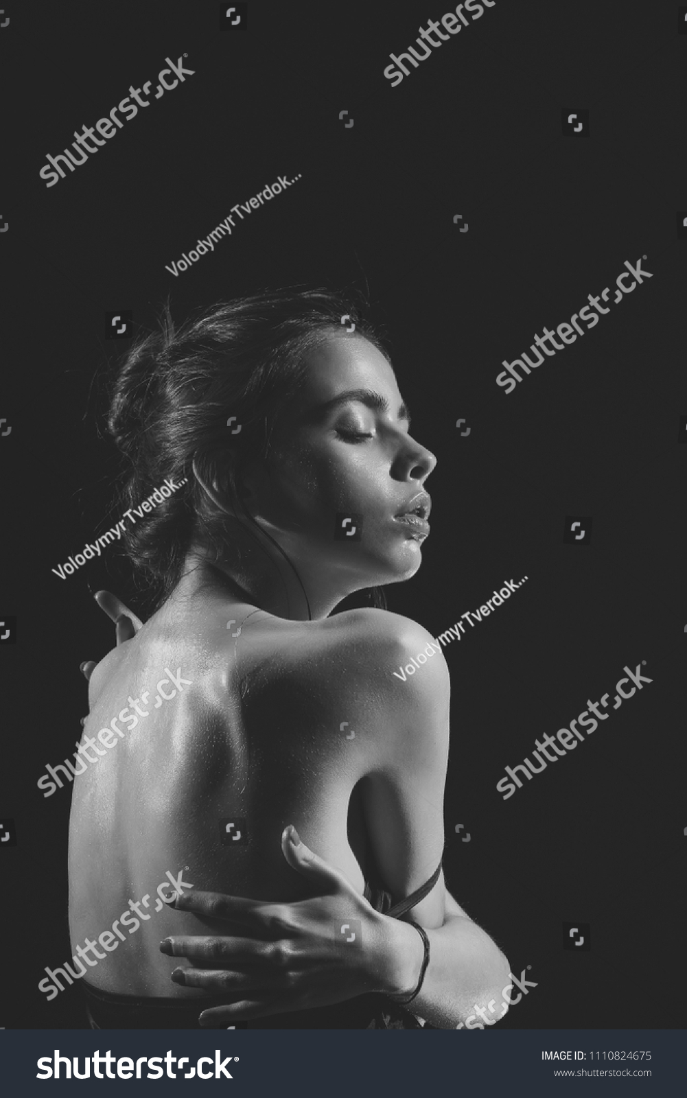 fashion portrait. Girl with oily or wet skin on black background. Woman with sensual face and bare back. Beauty, fashion, look. Skincare, moisture, wellness. Purity, perfection, sensuality concept. #1110824675