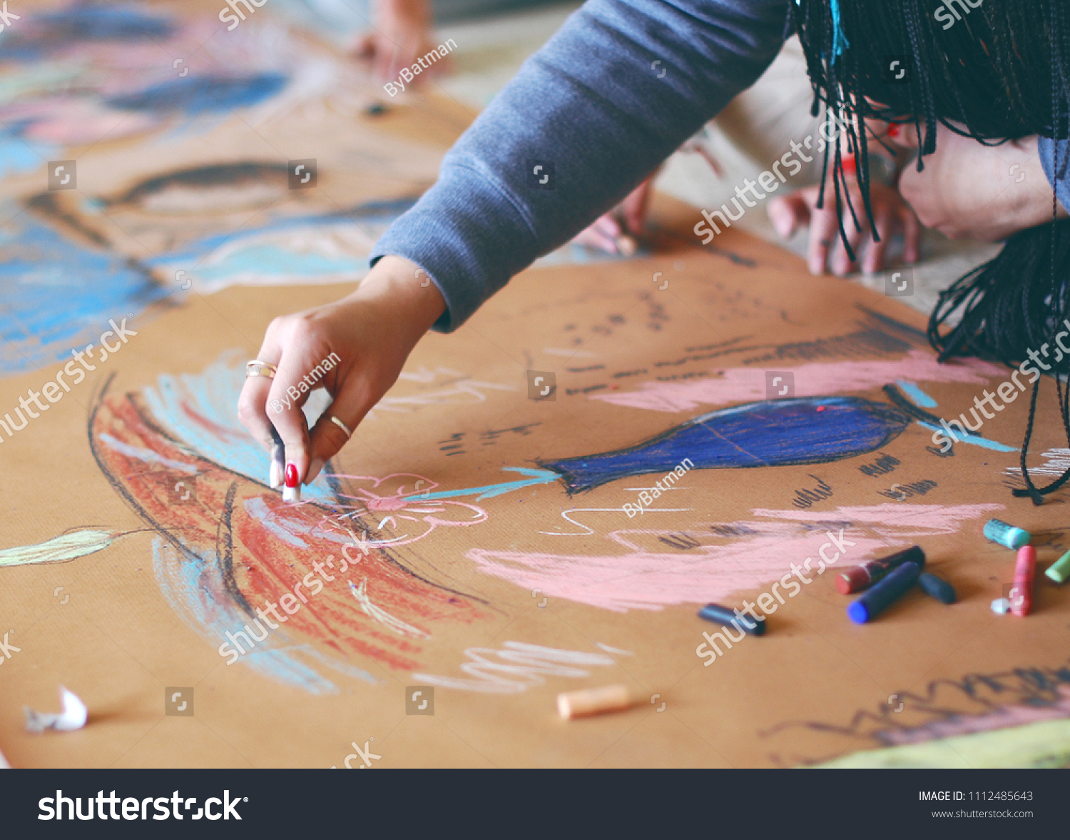 woman is painting with a chalk picture in an art studio on the floor #1112485643