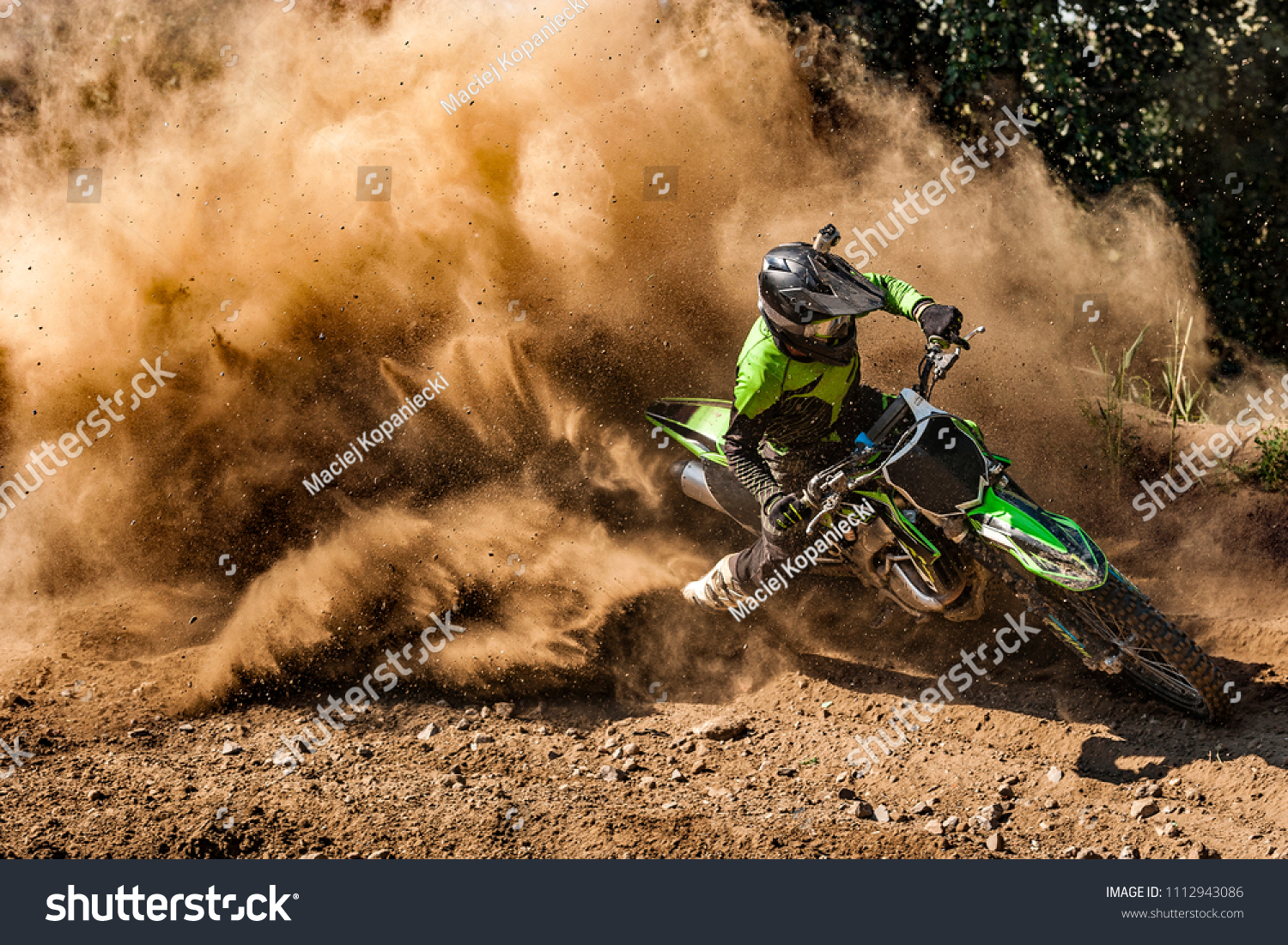 Motocross rider creates a huge cloud of dust and debris #1112943086
