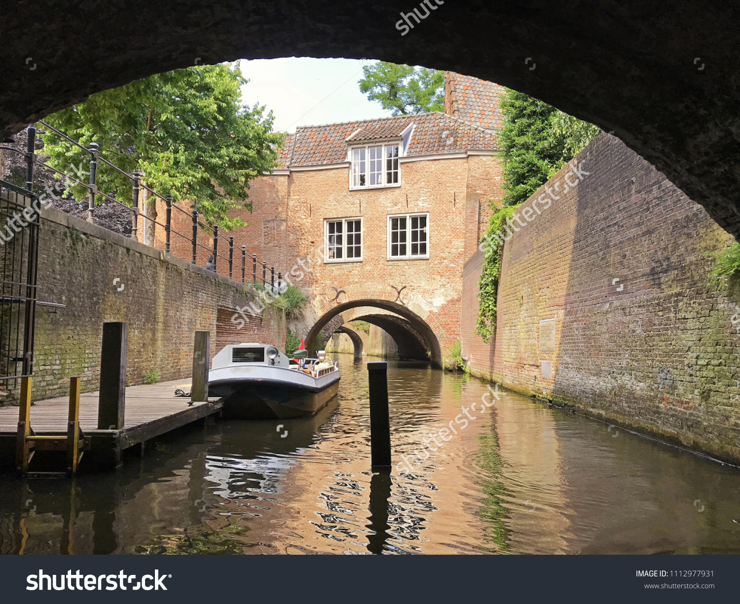 Beautiful canal in Den Bosch wtih a boat, showing a reflection in the water with space for text.  #1112977931